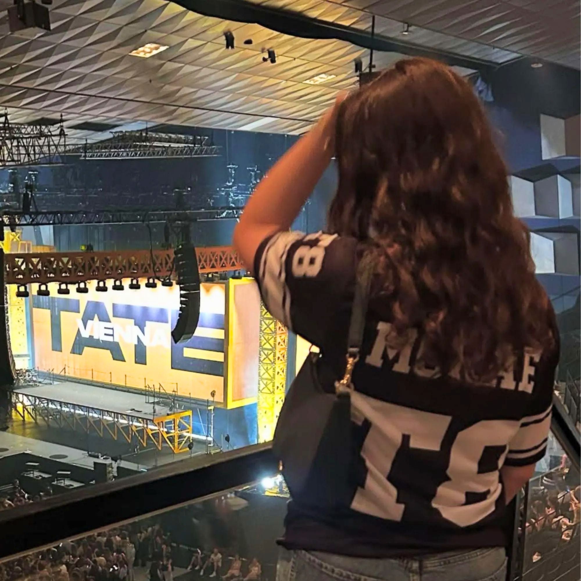 Person taking a photo of a large screen displaying 'Tate Modern' inside a building.