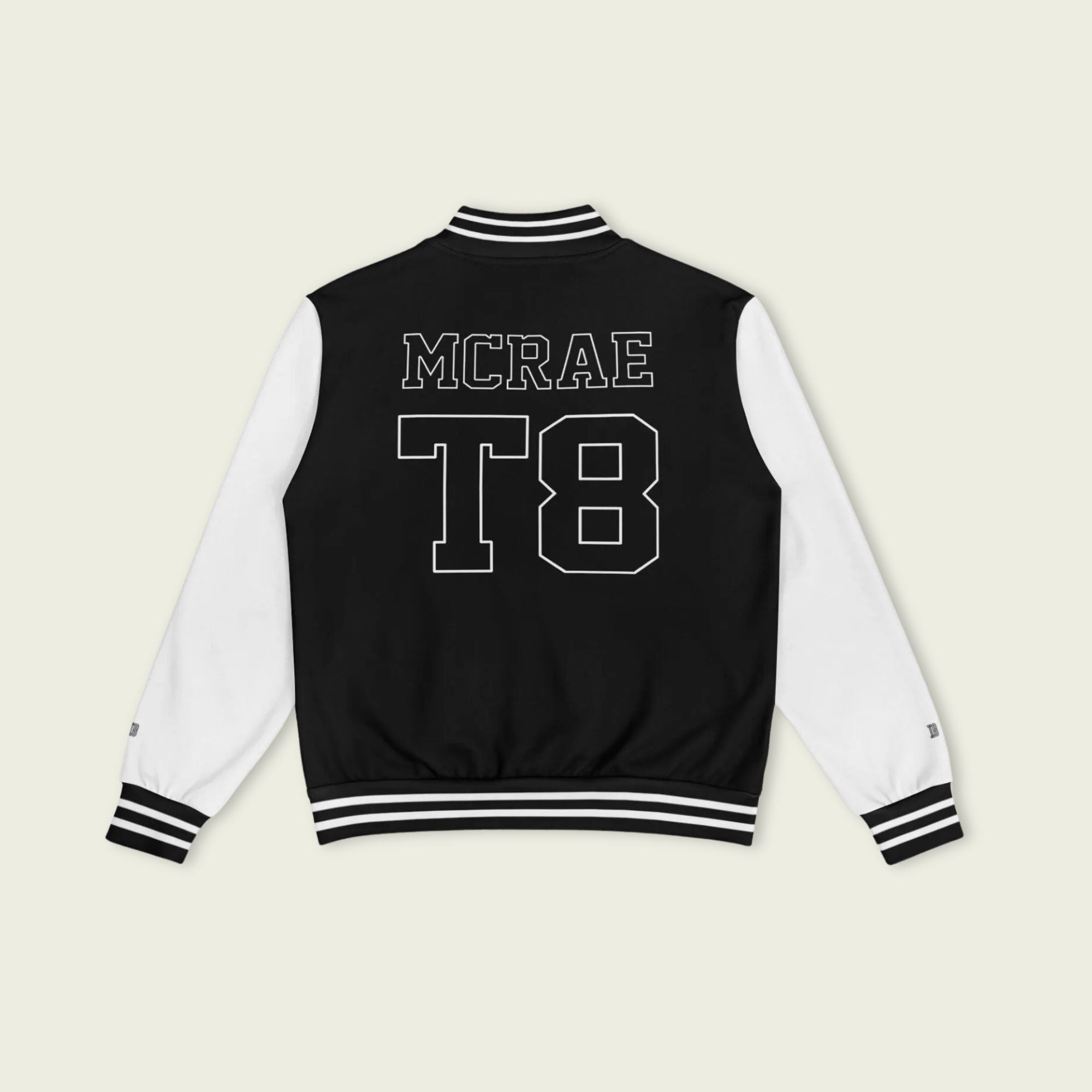 A black and white varsity jacket showing T8, 23, and Tate Mcrae in whte on the front and back.