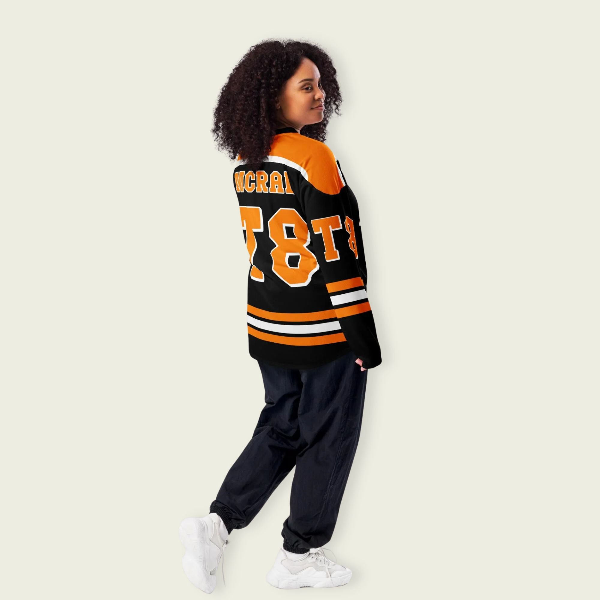 A black, orange, and white hockey jersey with the name Mcrae in orange on the front and back. Also T8 in orange on the front and back.