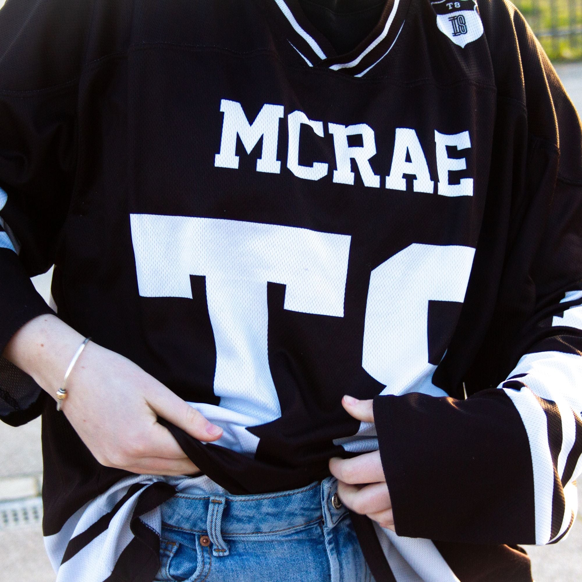 A black and white hockey jersey with the name Mcrae in white on the front and back. Also T8 in white on the front and back.