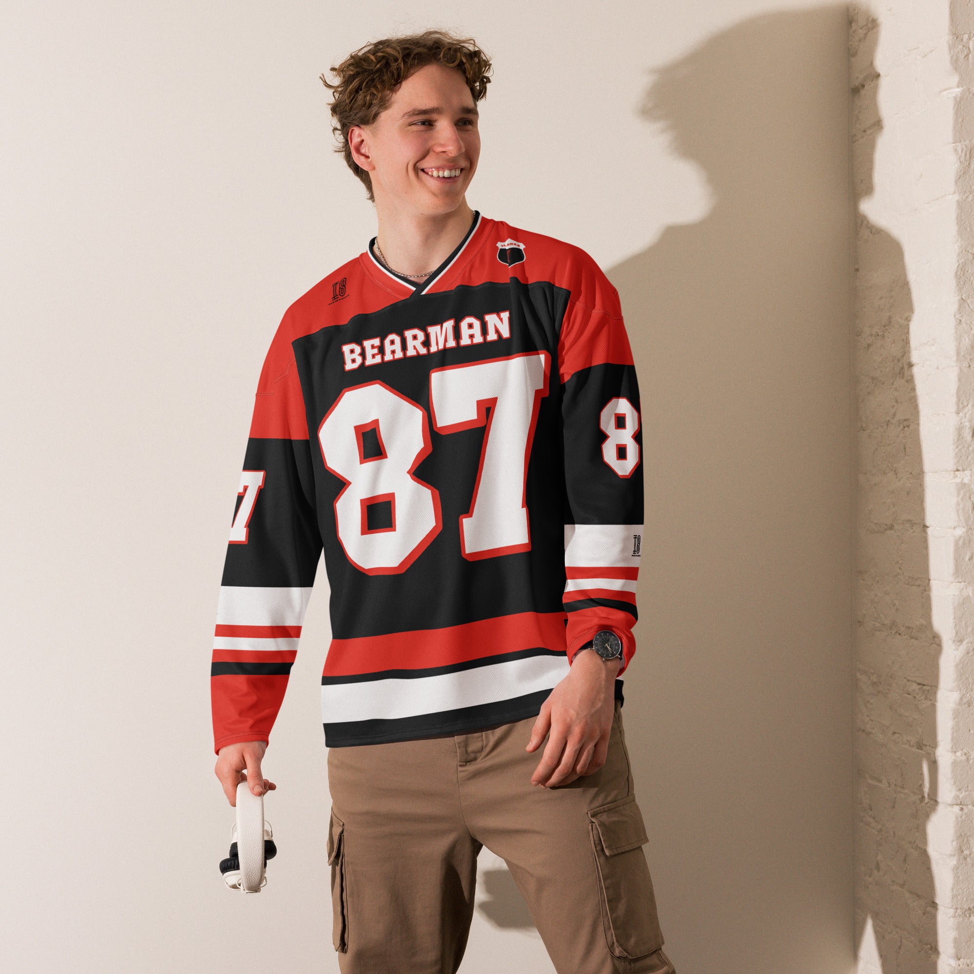 A red and black hockey jersey with Oliver Bearman's Haas F1 racing number 87 on the front and back in white, also the name Bearman is on the back and front in White.