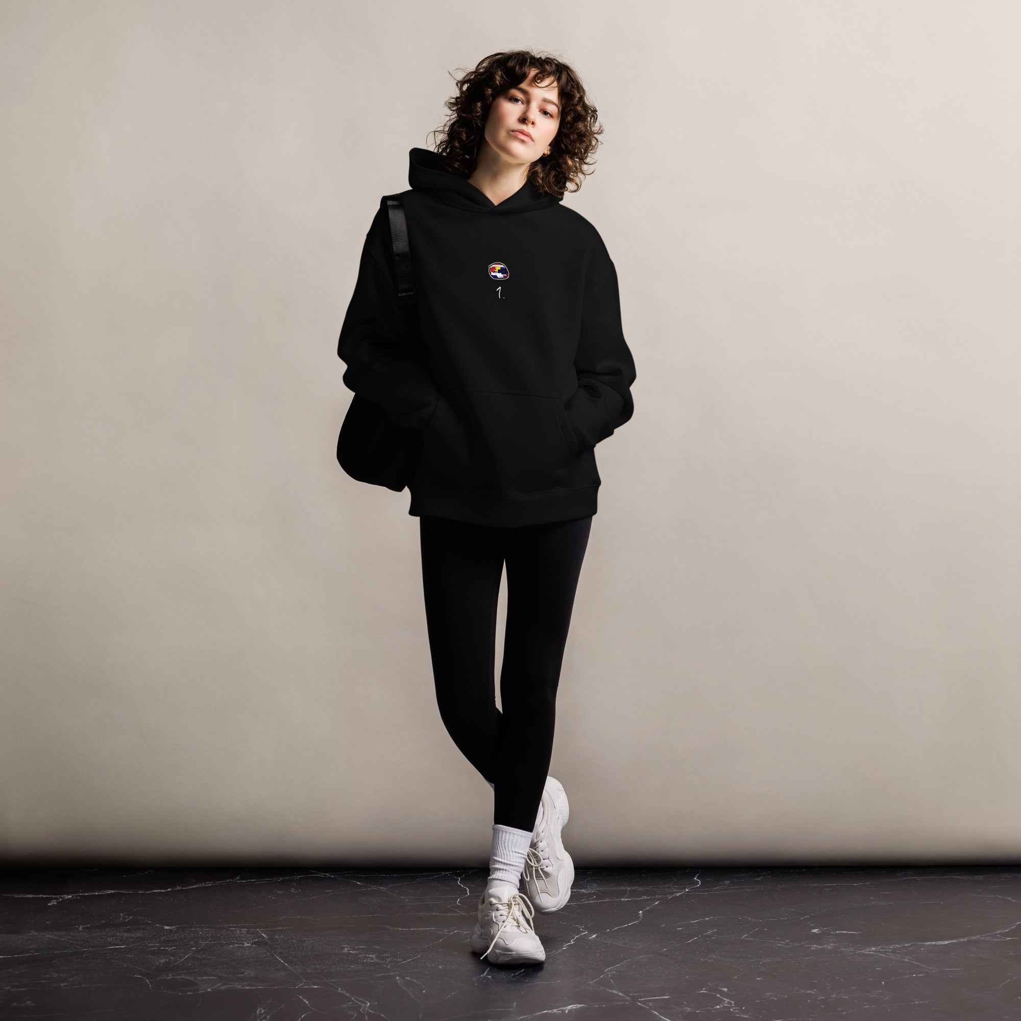 A black oversized hoodie with white text Max Verstappen's racing number 1 on the front and Verstappen's graphic helmut on the front.