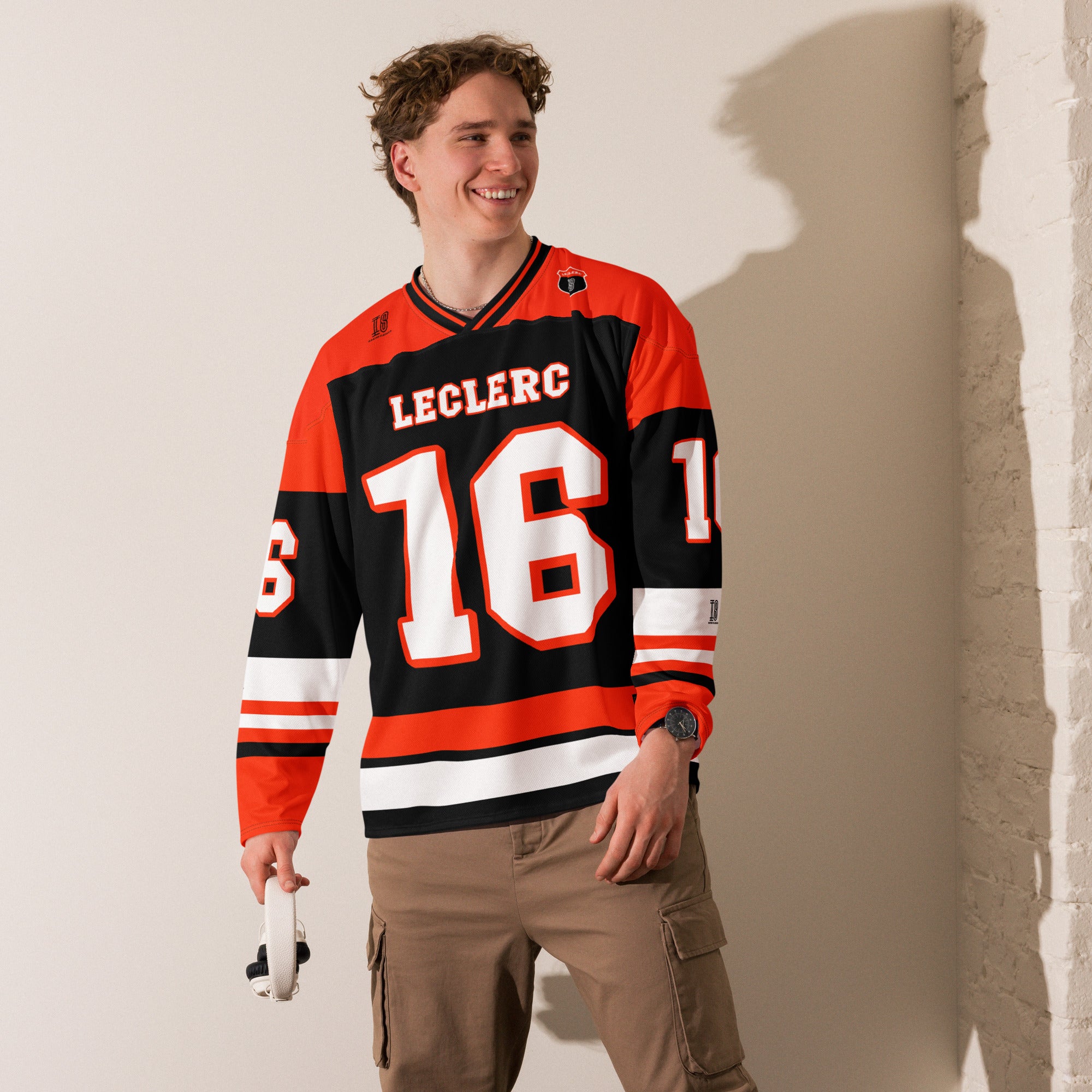 A red and black hockey jersey with Charles Leclerc's Ferrari F1 racing number 16 in white on the front and back. It has the name Leclerc on the back and front in white as well.