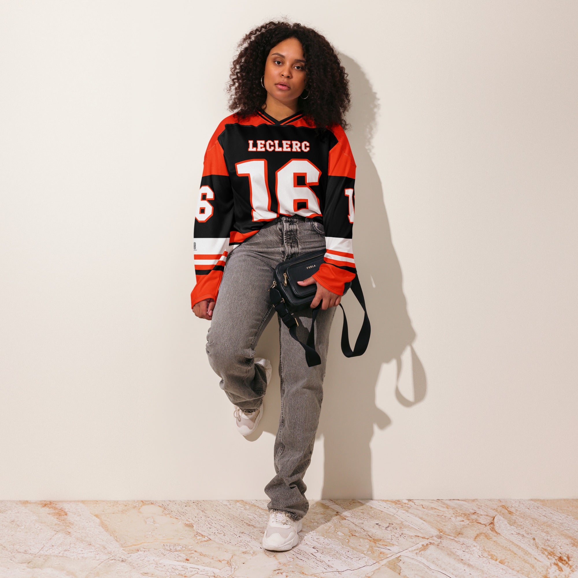 A red and black hockey jersey with Charles Leclerc's Ferrari F1 racing number 16 in white on the front and back. It has the name Leclerc on the back and front in white as well.