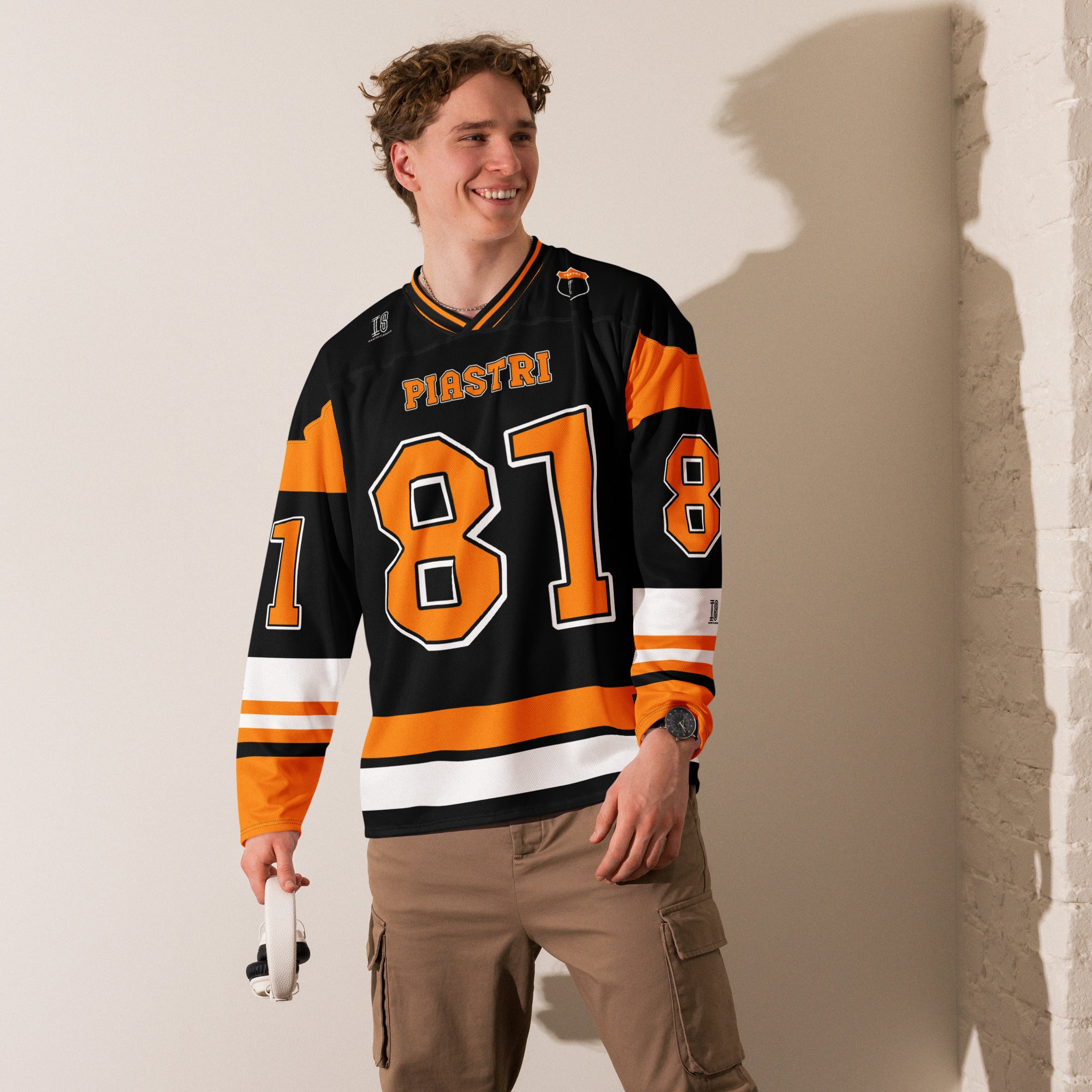 A black hockey jersey with Osacr Piastri's mclaren F1 racing number 81 on the front and back in papaya orange, also the name norris is on the back and front in orange