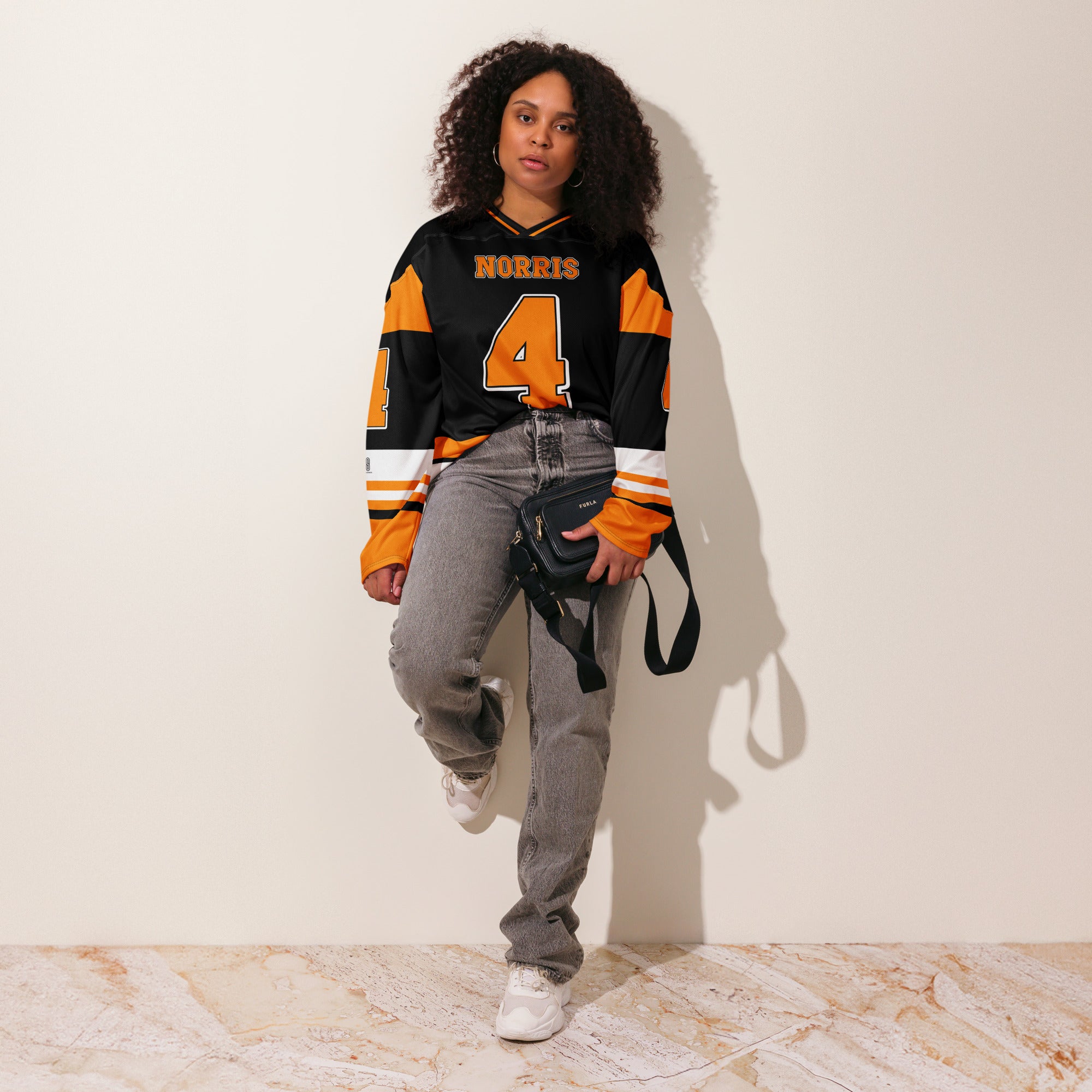 A black hockey jersey with Lando Norris mclaren F1 racing number 4 on the front and back in papaya orange, also the name norris is on the back and front in orange