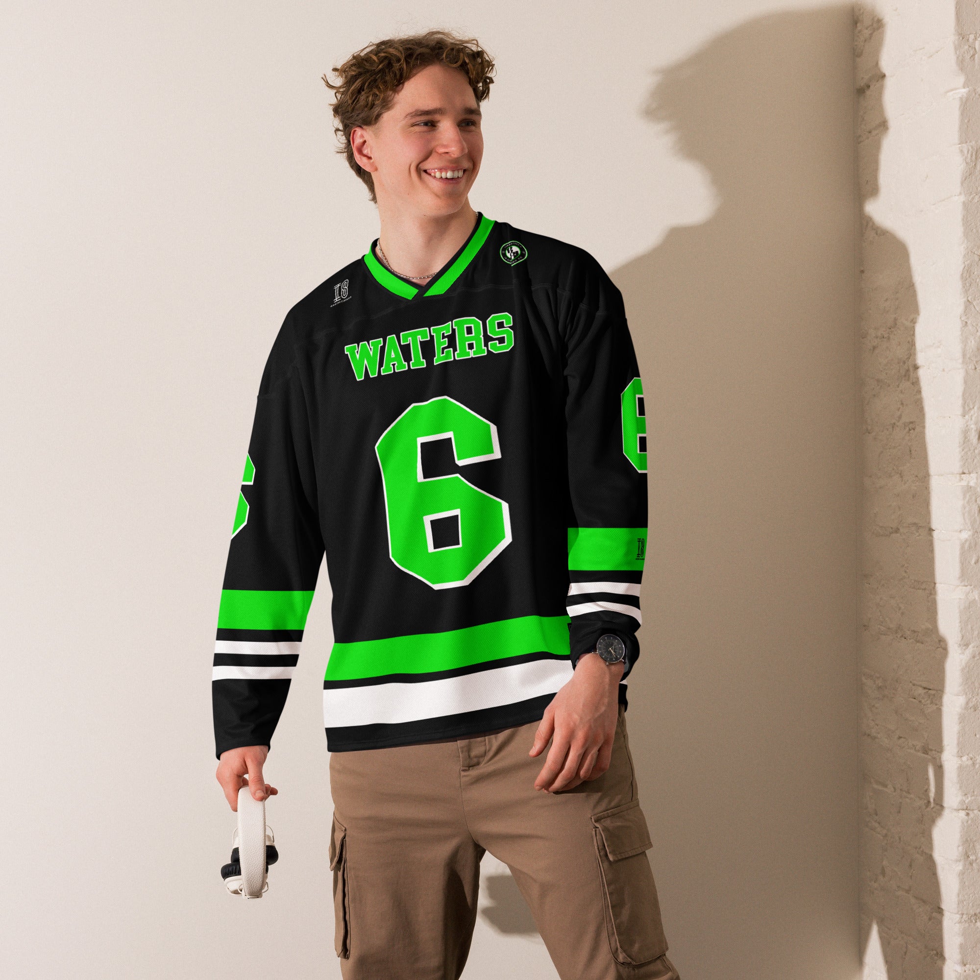 Person wearing a black hockey jersey with green accents and 'WATERS' and number '6', standing against a plain wall.