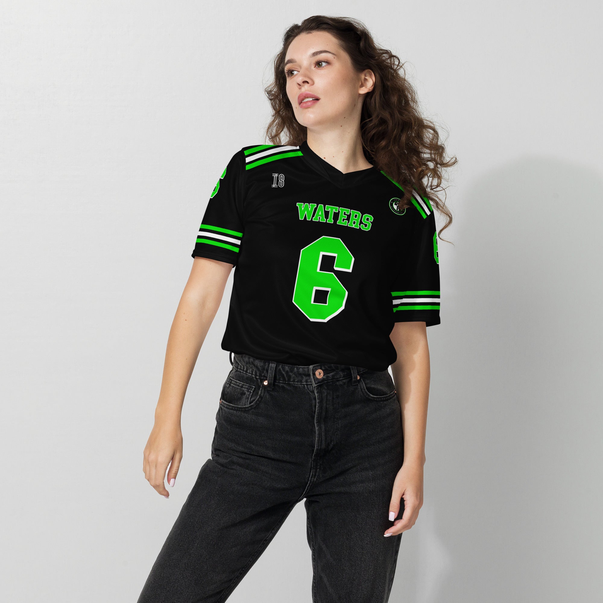 Person wearing a black sports jersey with green and white details on a plain background