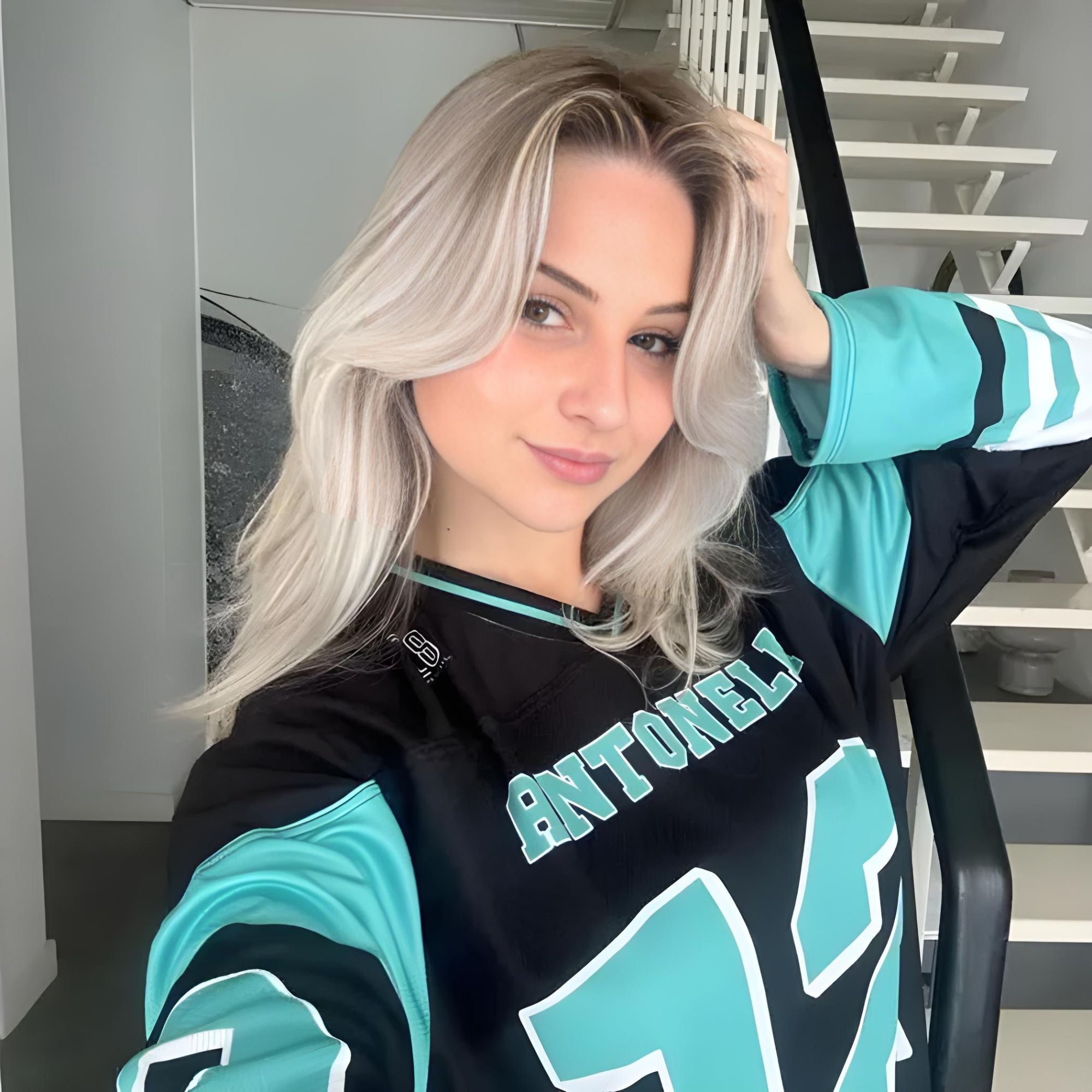 A black and turquoise hockey jersey with Andrea Kimi Antonelli's Mercedes F1 racing number 12 in turquoise on the front and back. It has the name Antonelli on the back and front in turquoise as well.