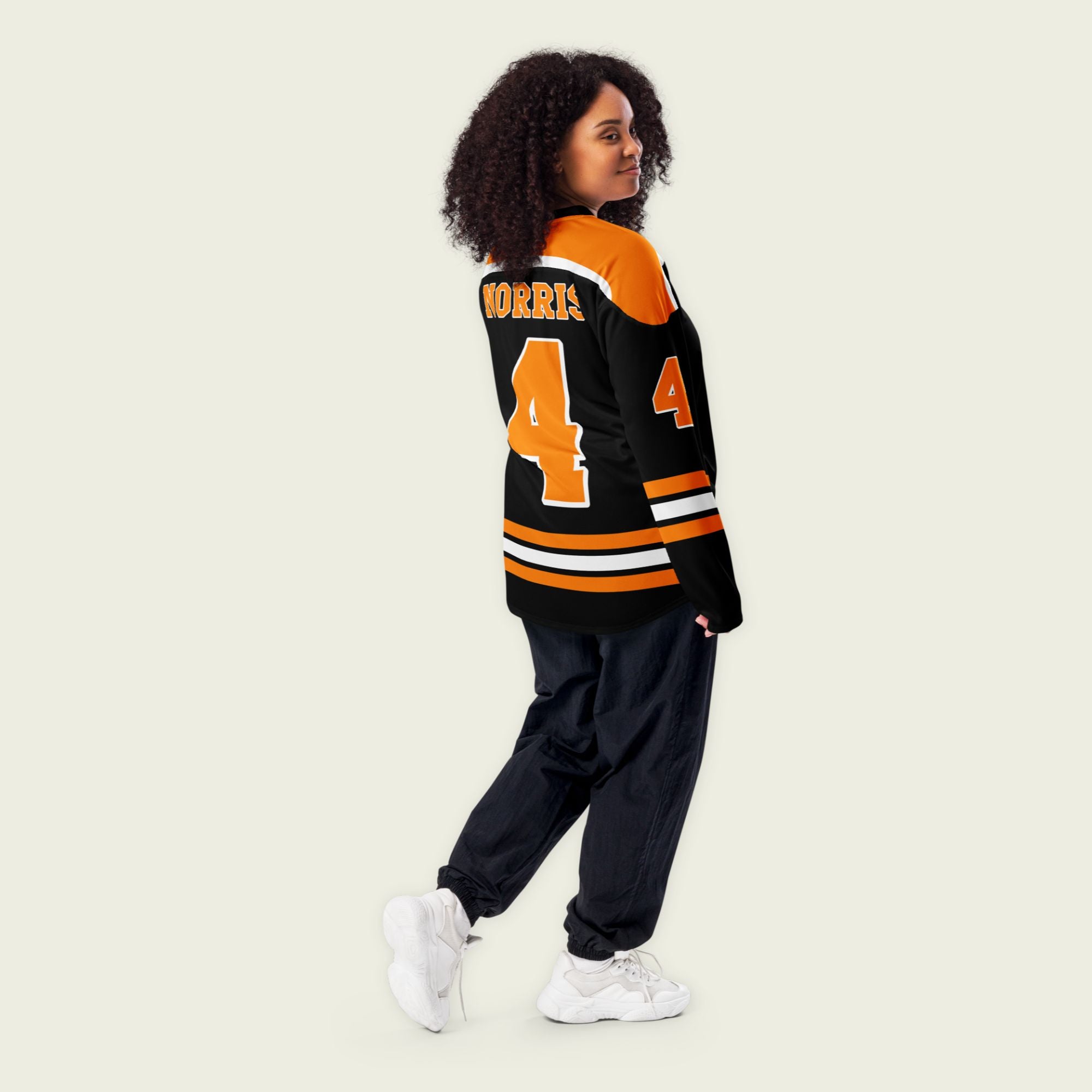 A black hockey jersey with lando norris's mclaren F1 racing number 4 on the front and the black. it has oragne stripesin the top, bottom, and arms. WIth his last name norris on the front and back.