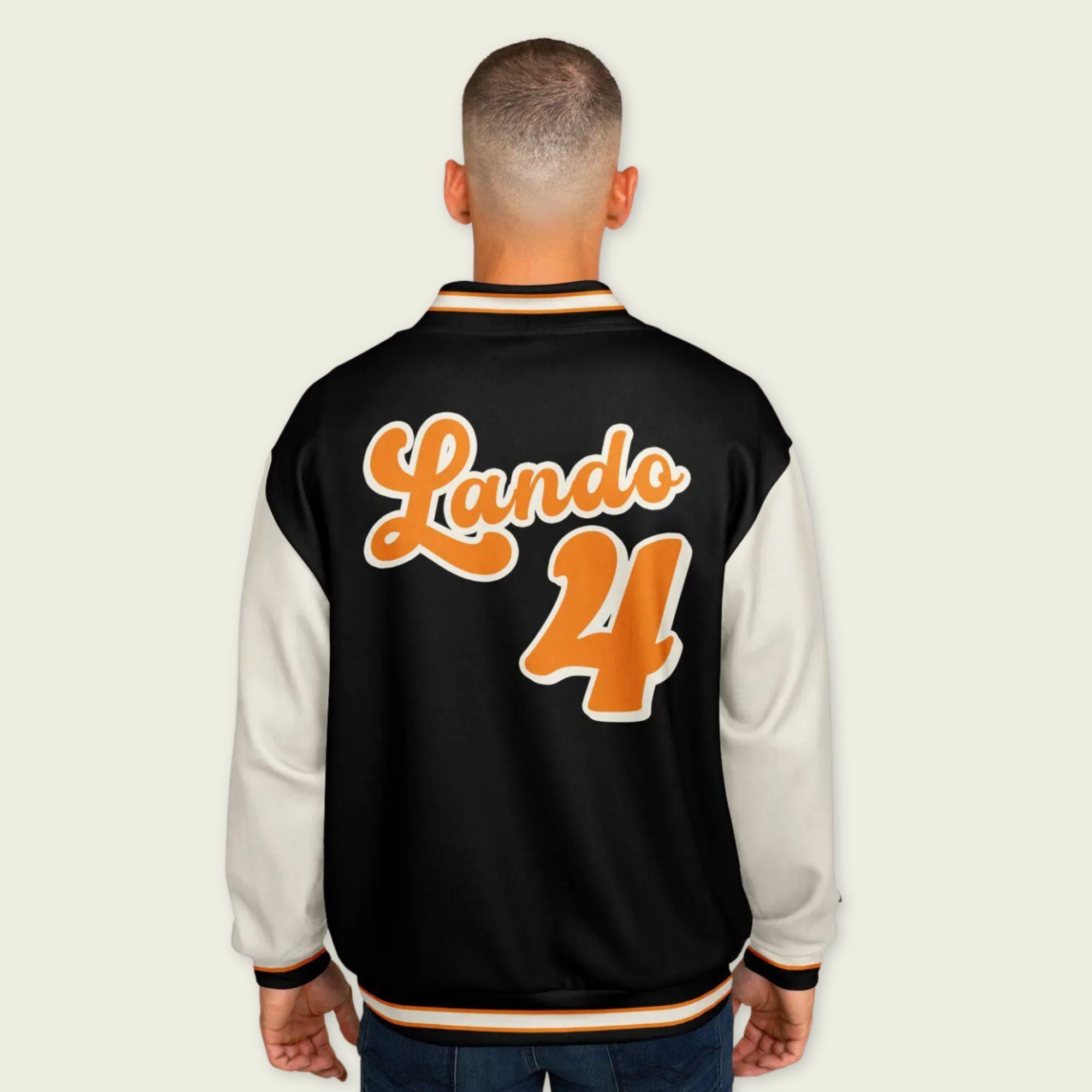 A black, papaya orange, and tan, varsity jacket with Oscar Piastri's McLaren F1 racing number 81 in orange on the front and back.