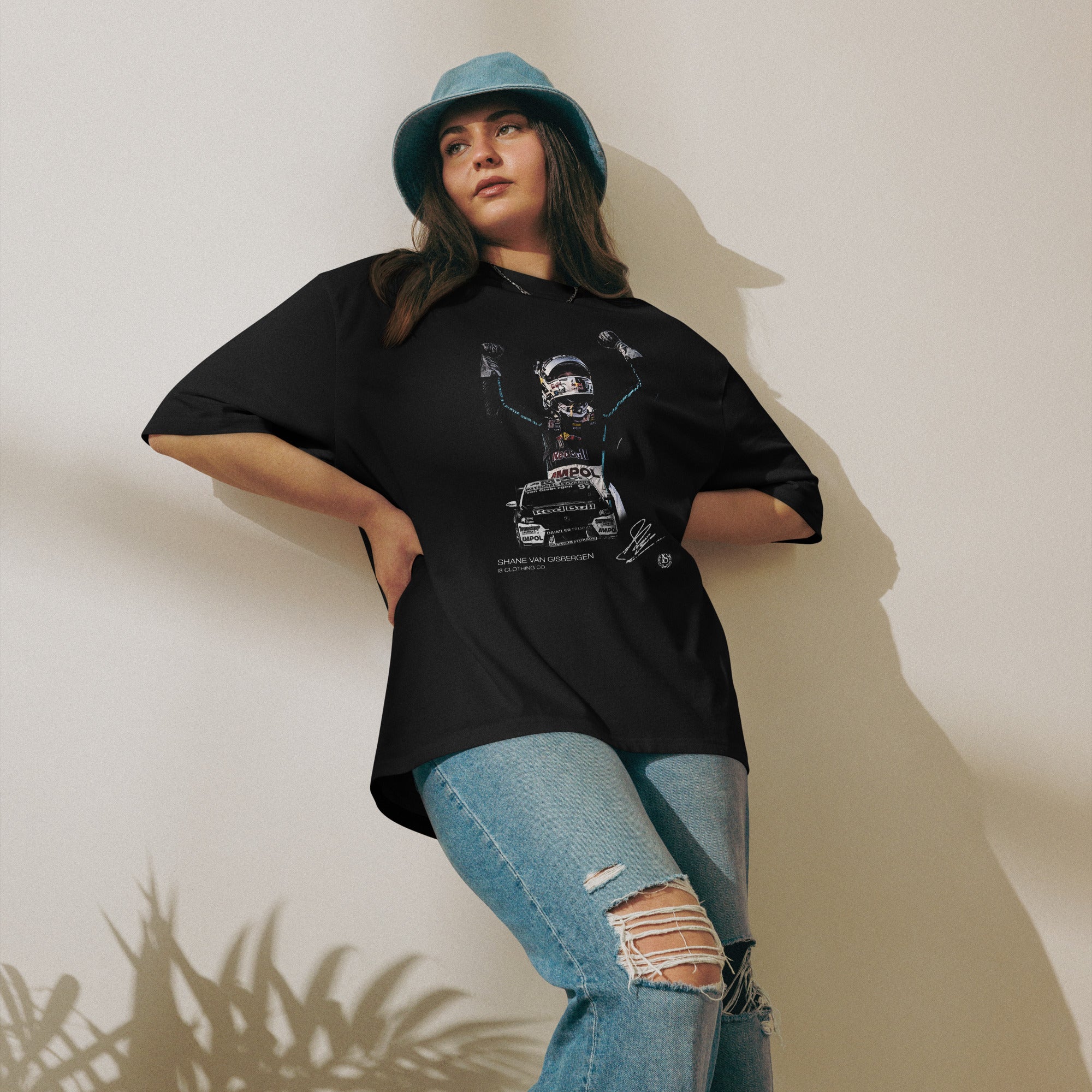 Person wearing a black oversized t-shirt with graphic design and light blue jeans against a plain background
