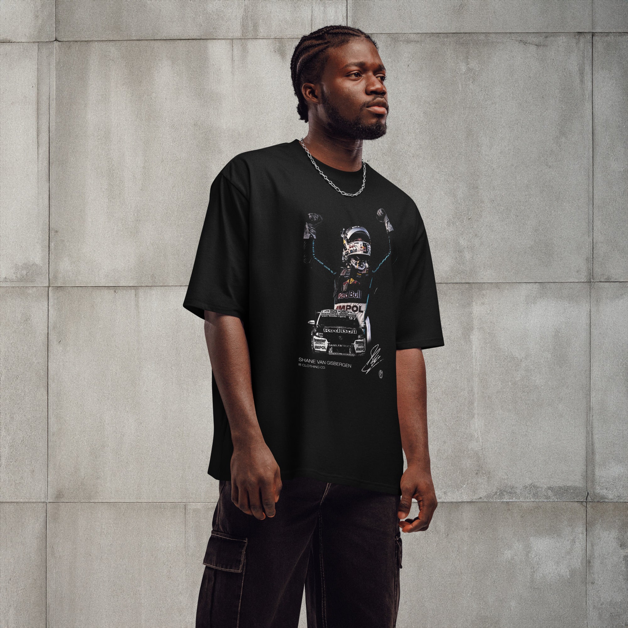 Man wearing a black t-shirt with graphic design against a gray concrete wall