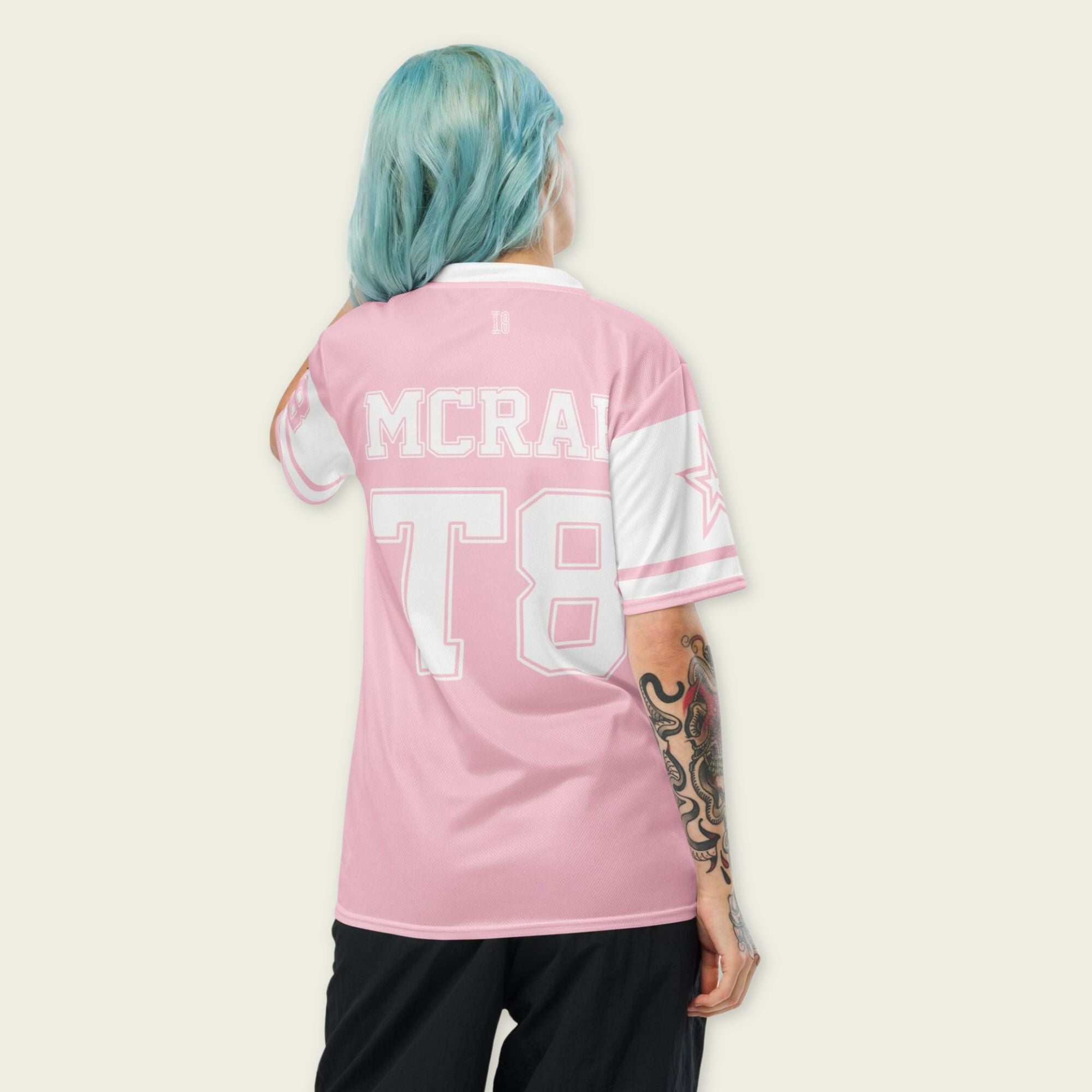 A pink and white football jersey with Tate Mcare on the back and front in white with a white outline.