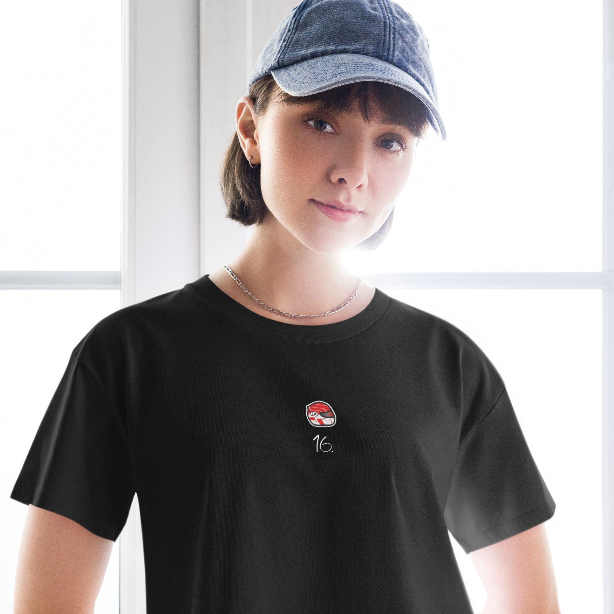 Person wearing a black t-shirt with a logo and a cap indoors