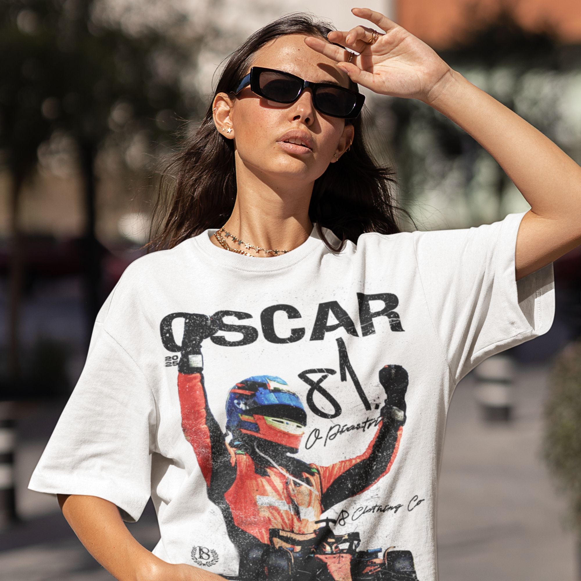 Woman wearing a white t-shirt with a graphic design and text, standing outdoors.