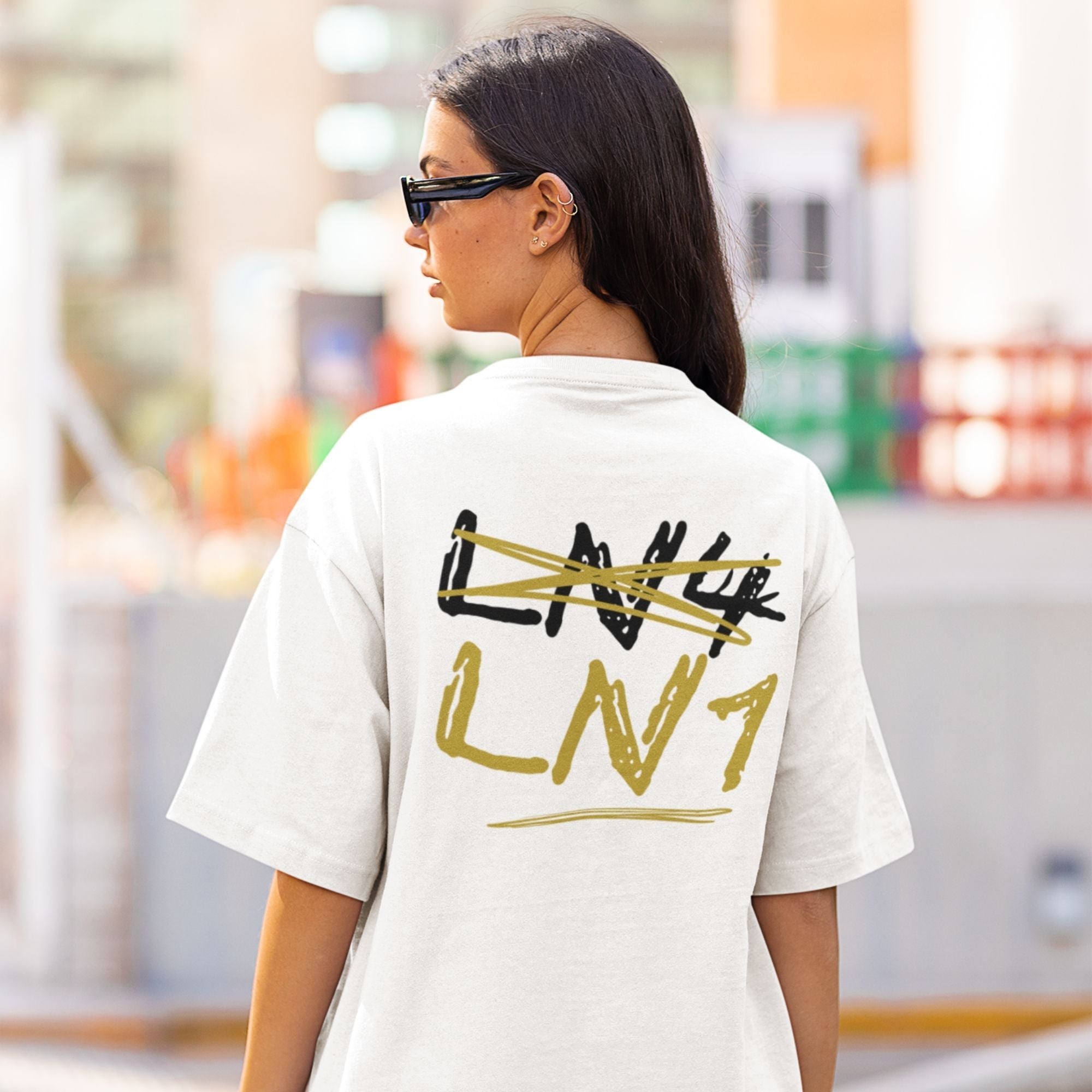 Person wearing a white t-shirt with 'LVN' design, standing outdoors.