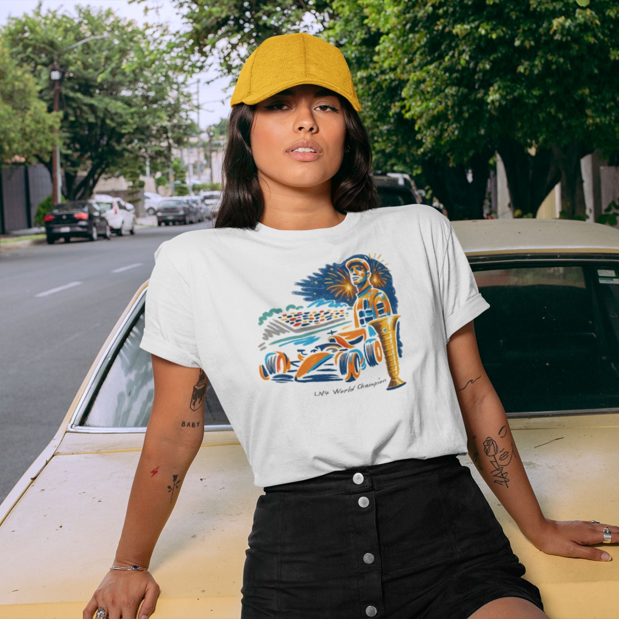 Person wearing a white t-shirt with a graphic design, sitting on a vintage car.