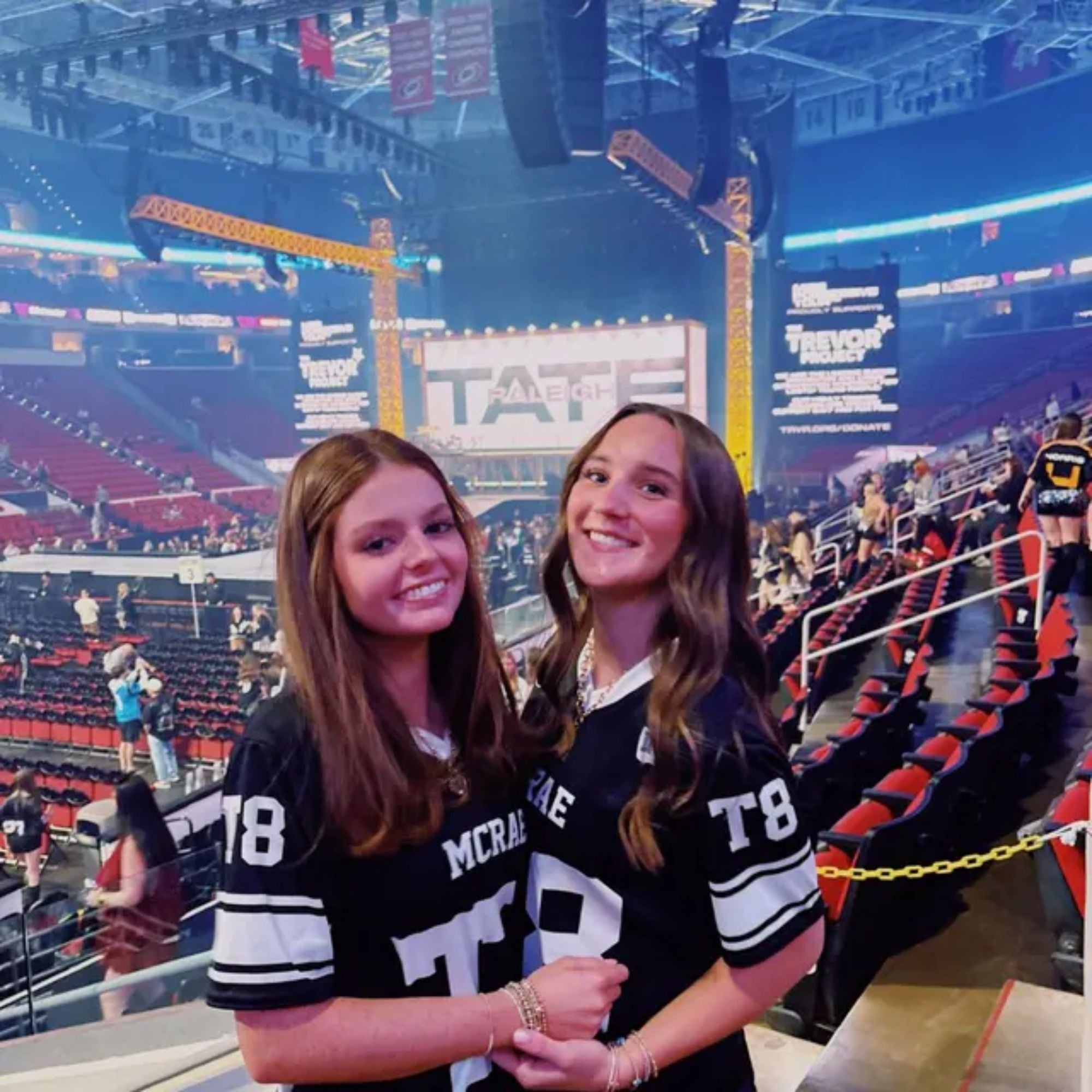 Two women in sports jerseys at a stadium with visible branding.
