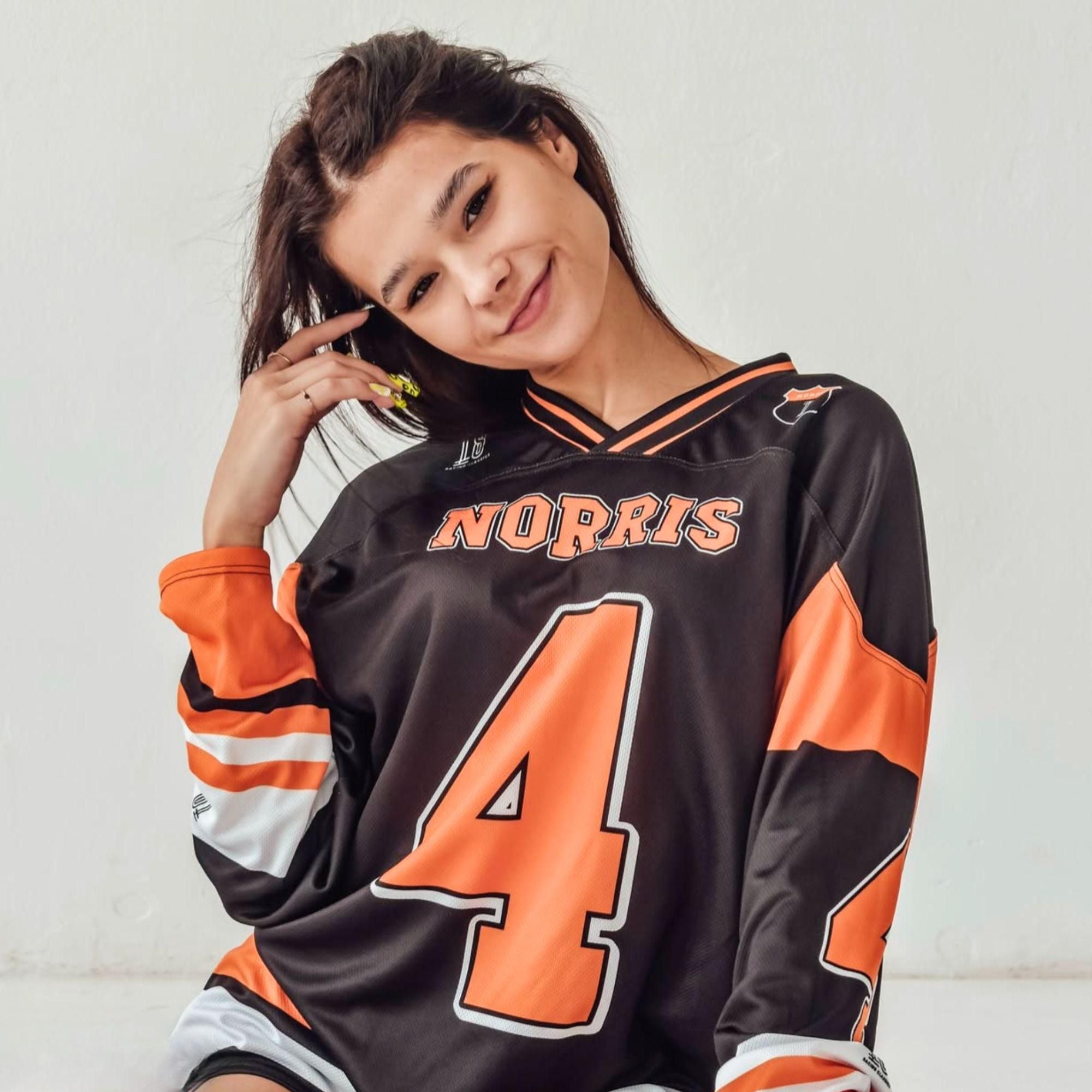 A black hockey jersey with Lando Norris mclaren F1 racing number 4 on the front and back in papaya orange, also the name norris is on the back and front in orange