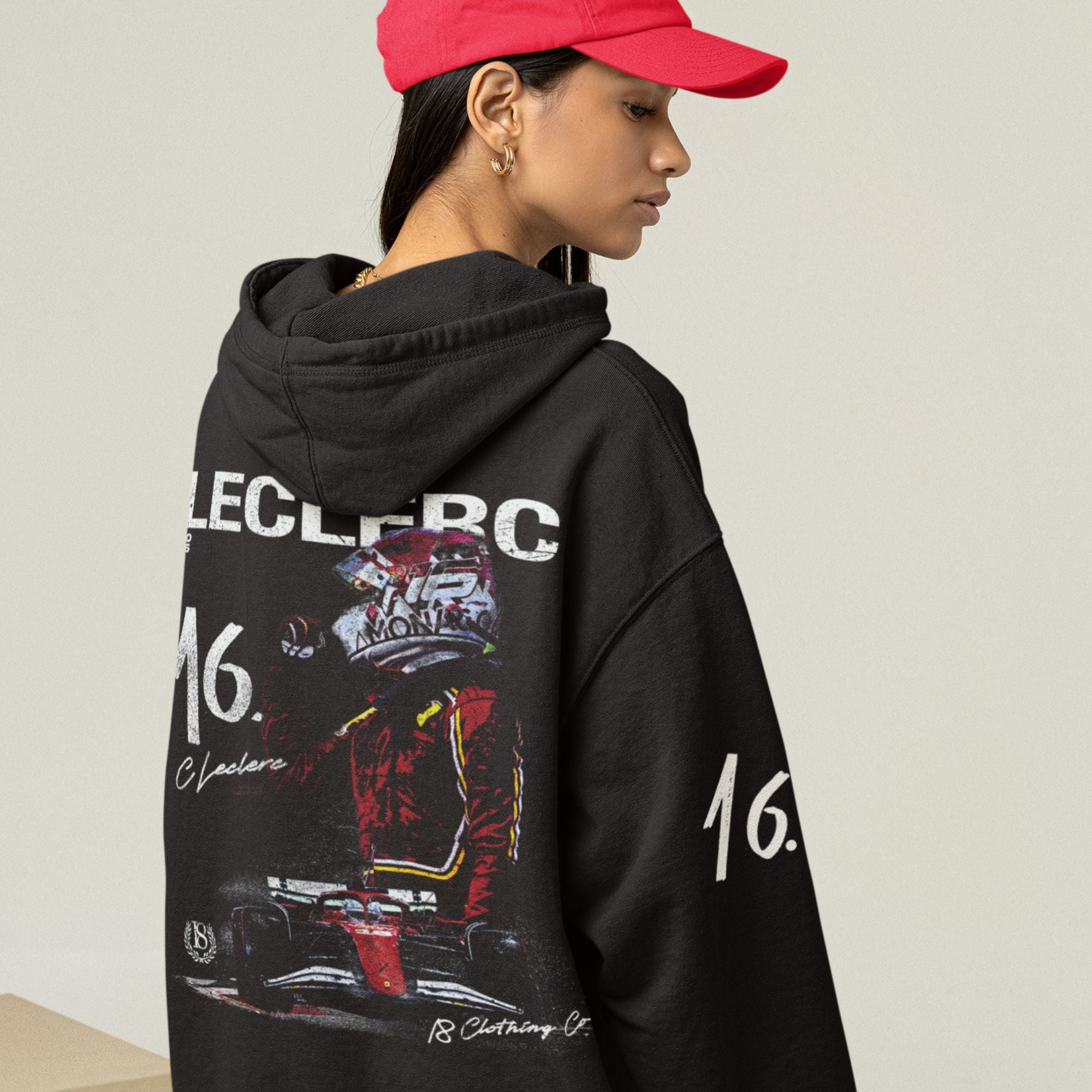 Person wearing a black hoodie with graphics and text, standing against a plain background