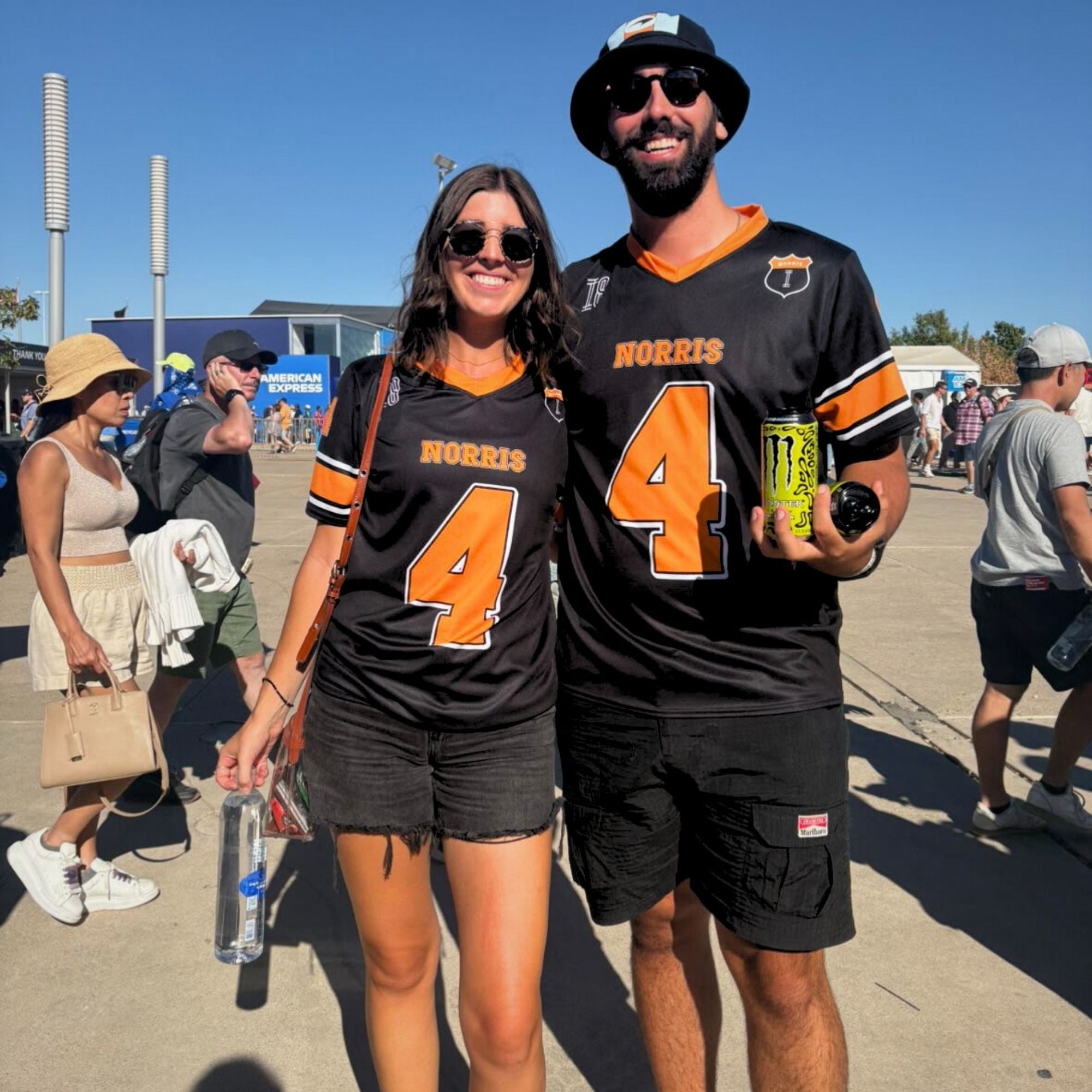 Two people wearing black and orange 'Norris 4' jerseys at an outdoor event.