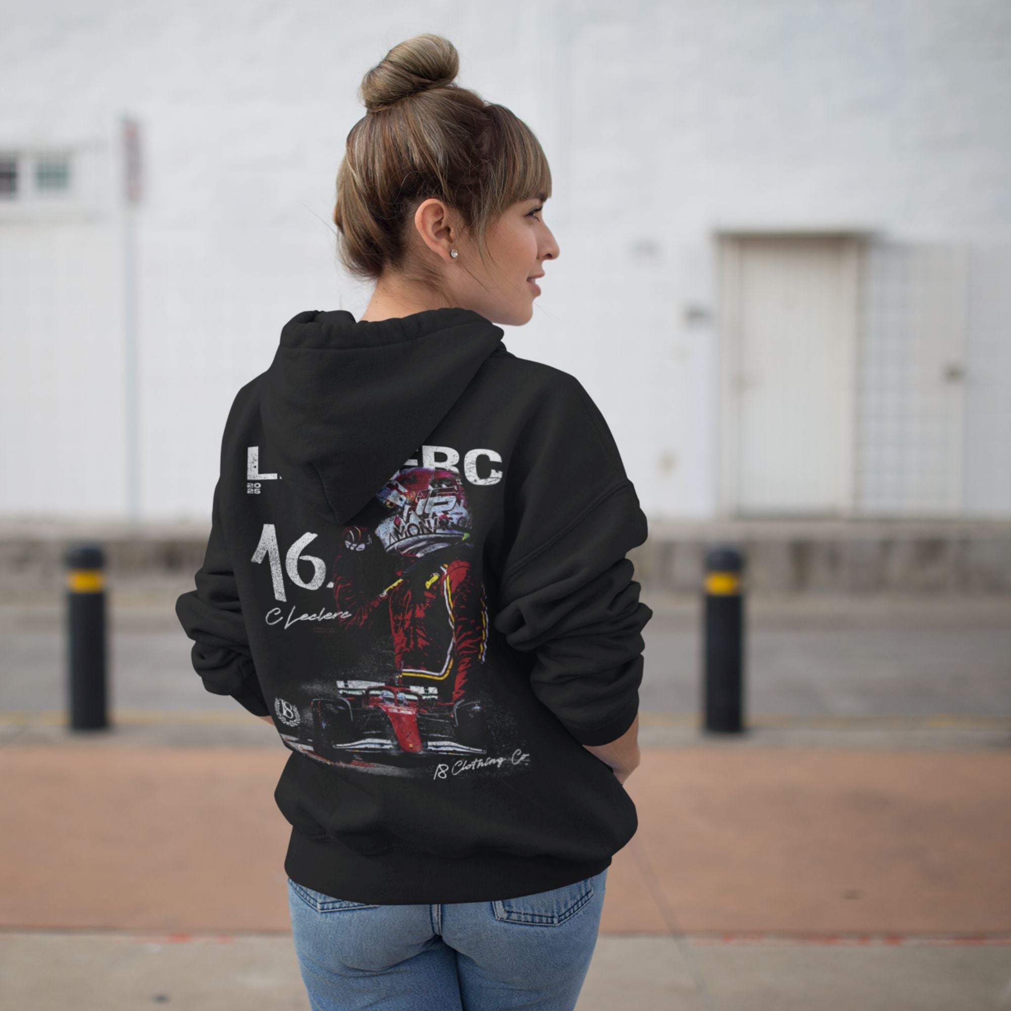 Person wearing a black hoodie with a Formula 1 car design on the back, standing outdoors.