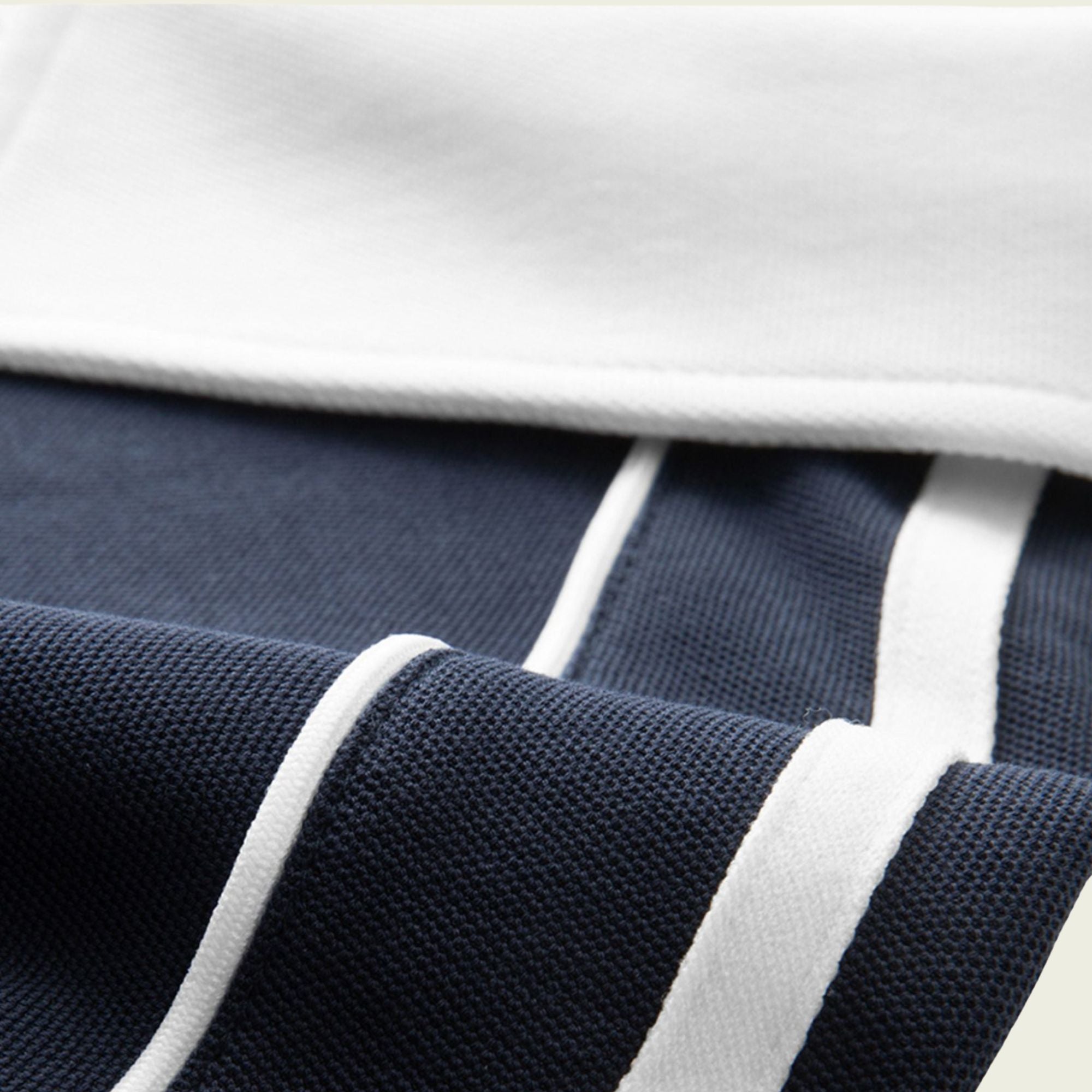 Close-up of a navy blue fabric with white stripes and a white border.