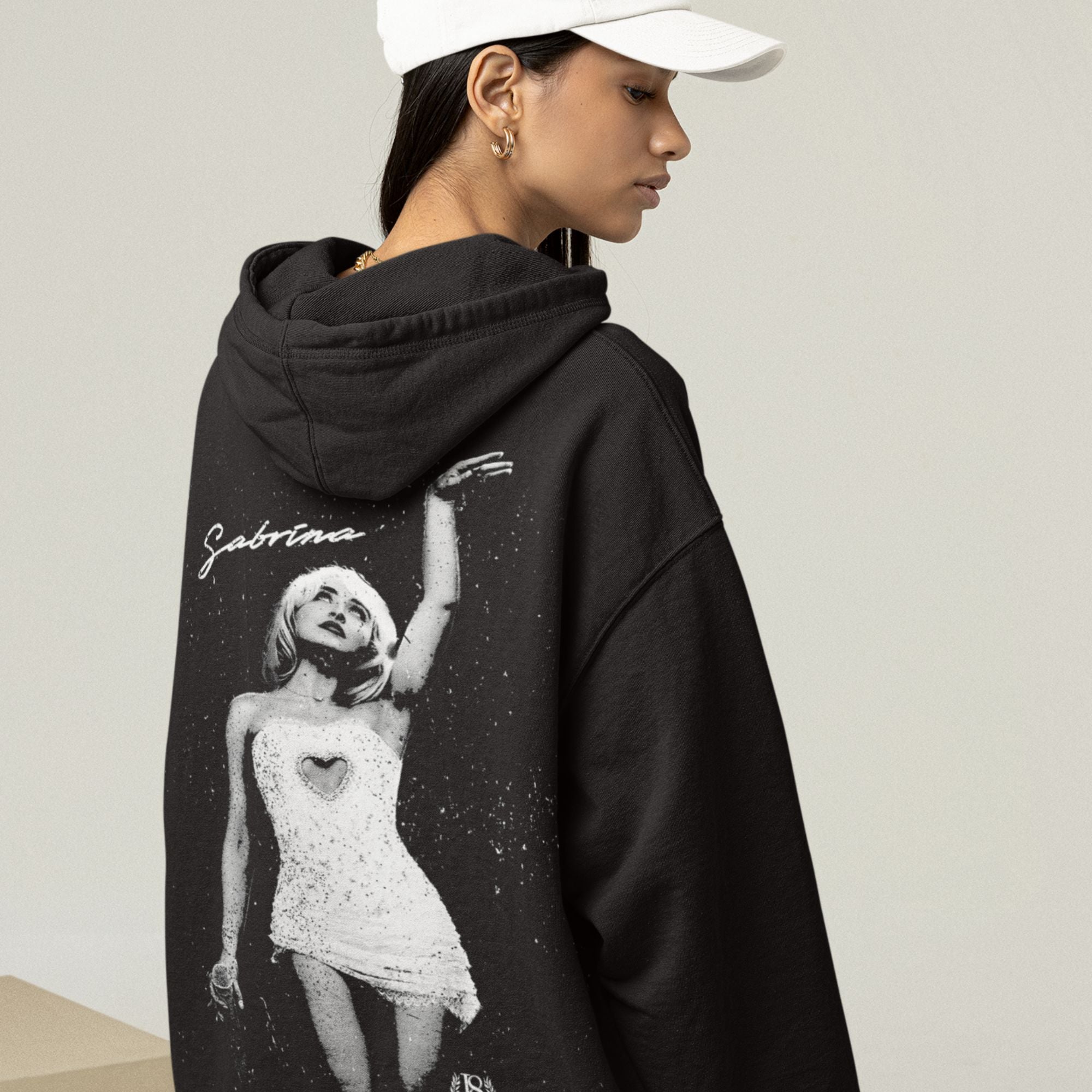 Person wearing a black hoodie with a graphic design on the back, standing against a plain background.