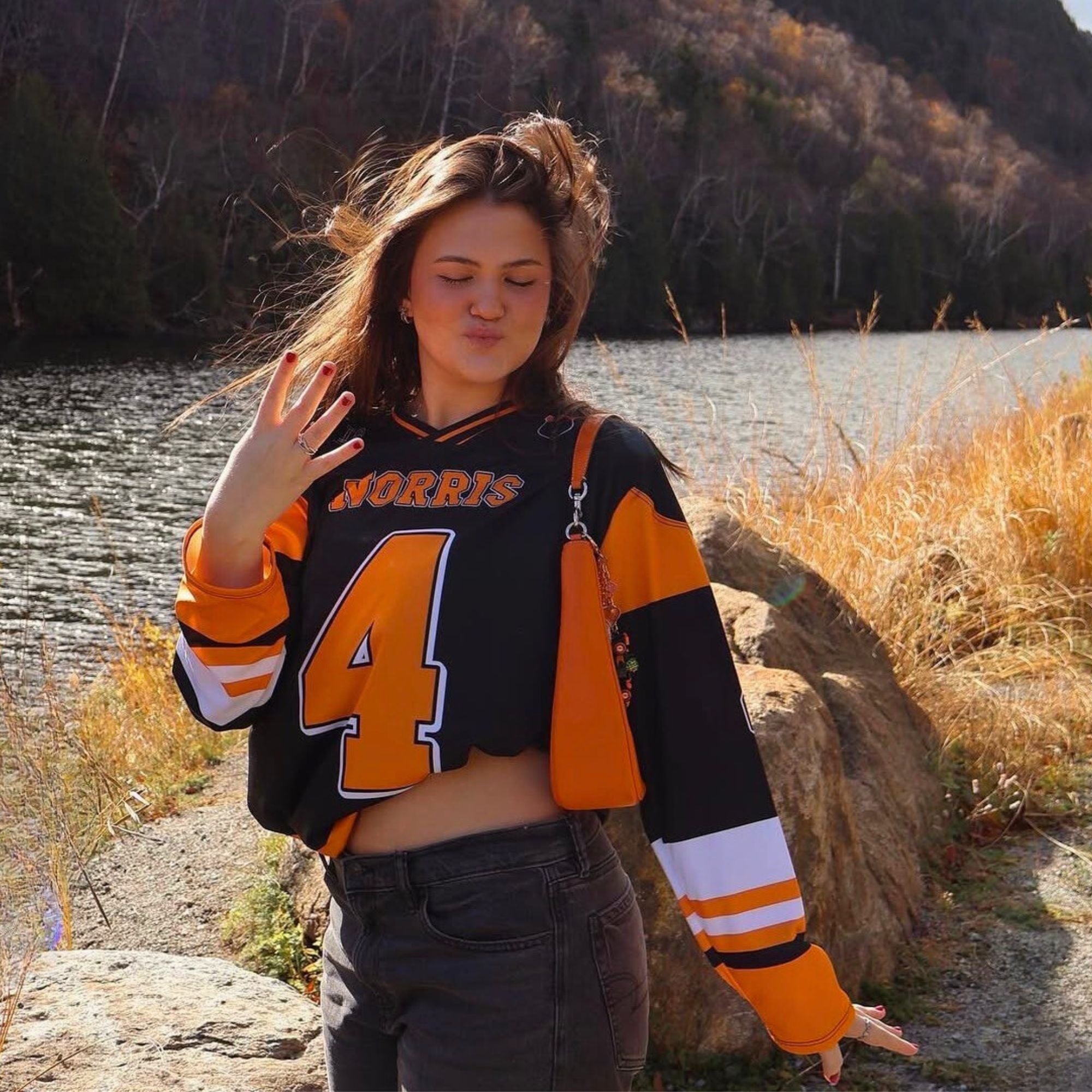 Person wearing a sports jersey by a lake with autumn foliage