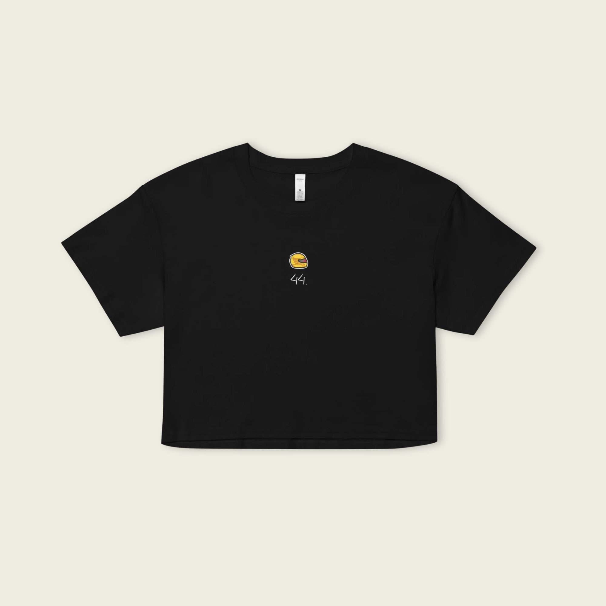 Black crop top with a small yellow graphic on a beige background