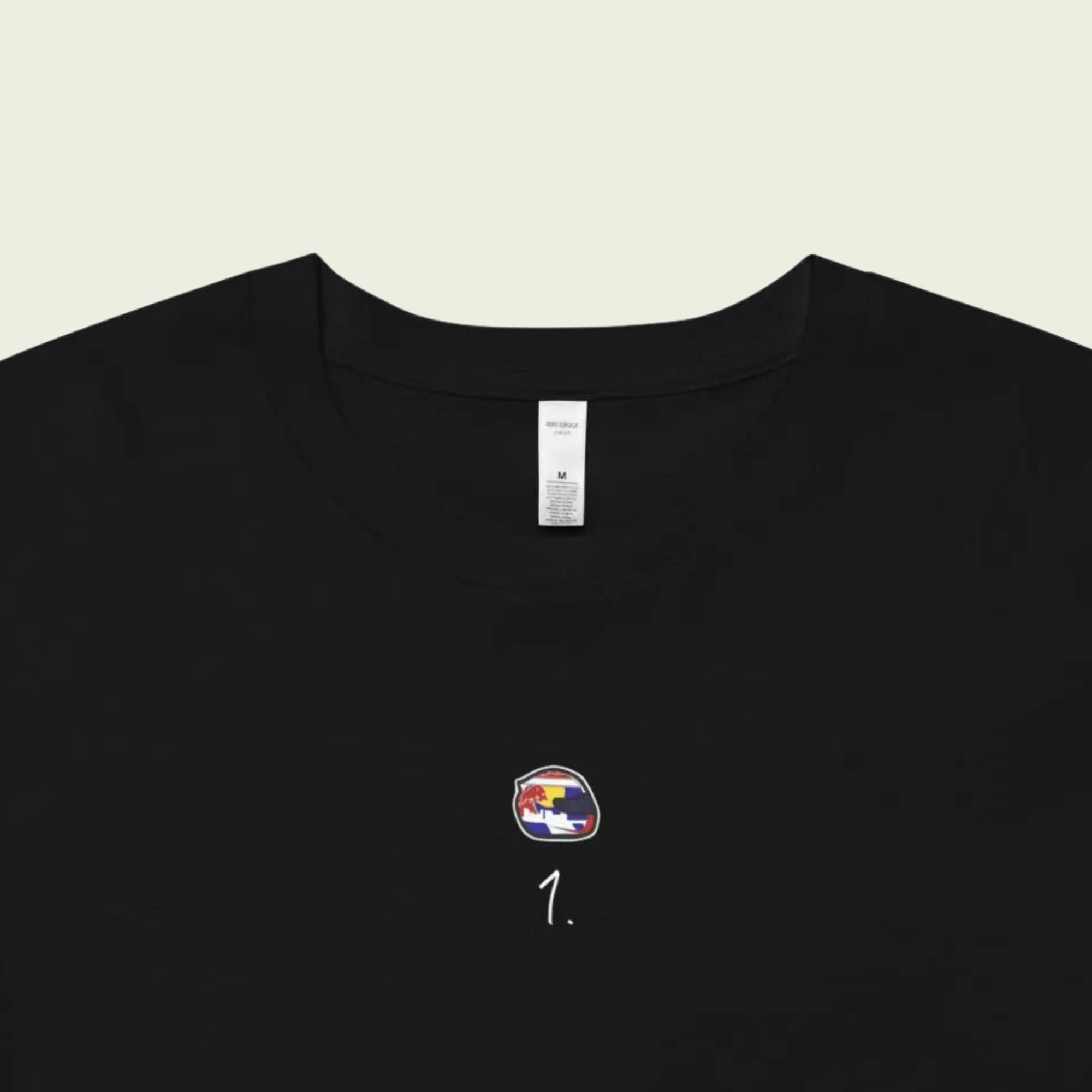 Black t-shirt with a small logo on the chest against a beige background