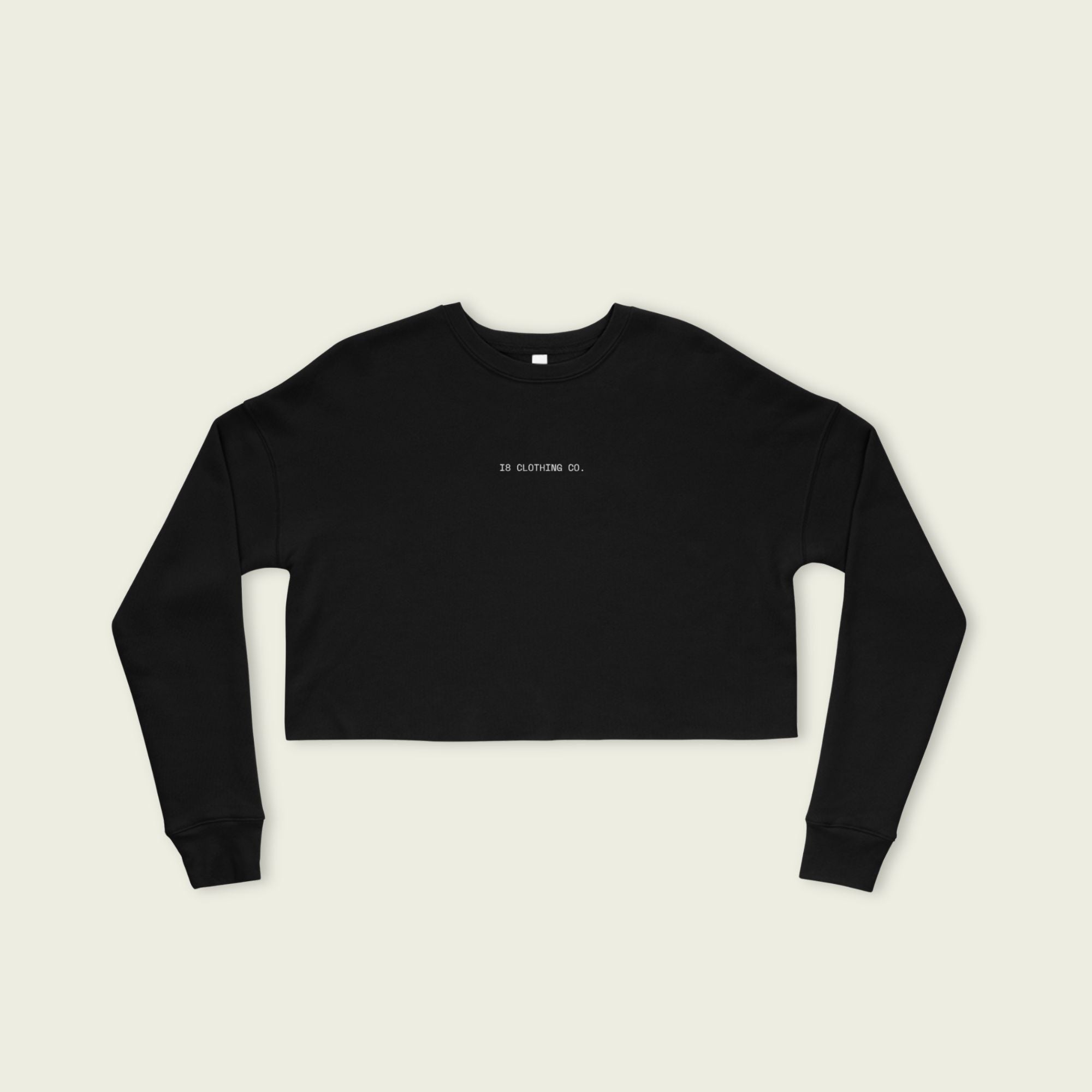 Black long-sleeve crop top with 'IN CLOTHING CO' text on a beige background