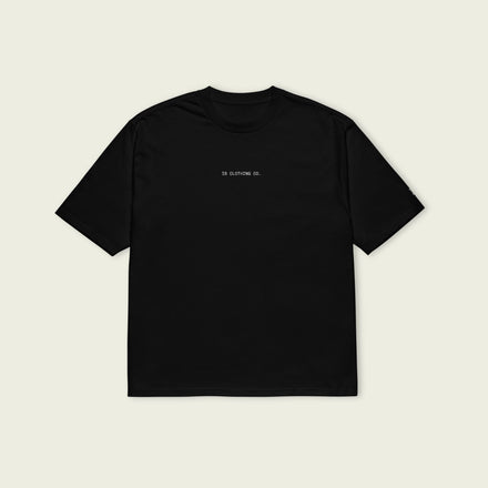 Black t-shirt with a small logo on the chest against a beige background