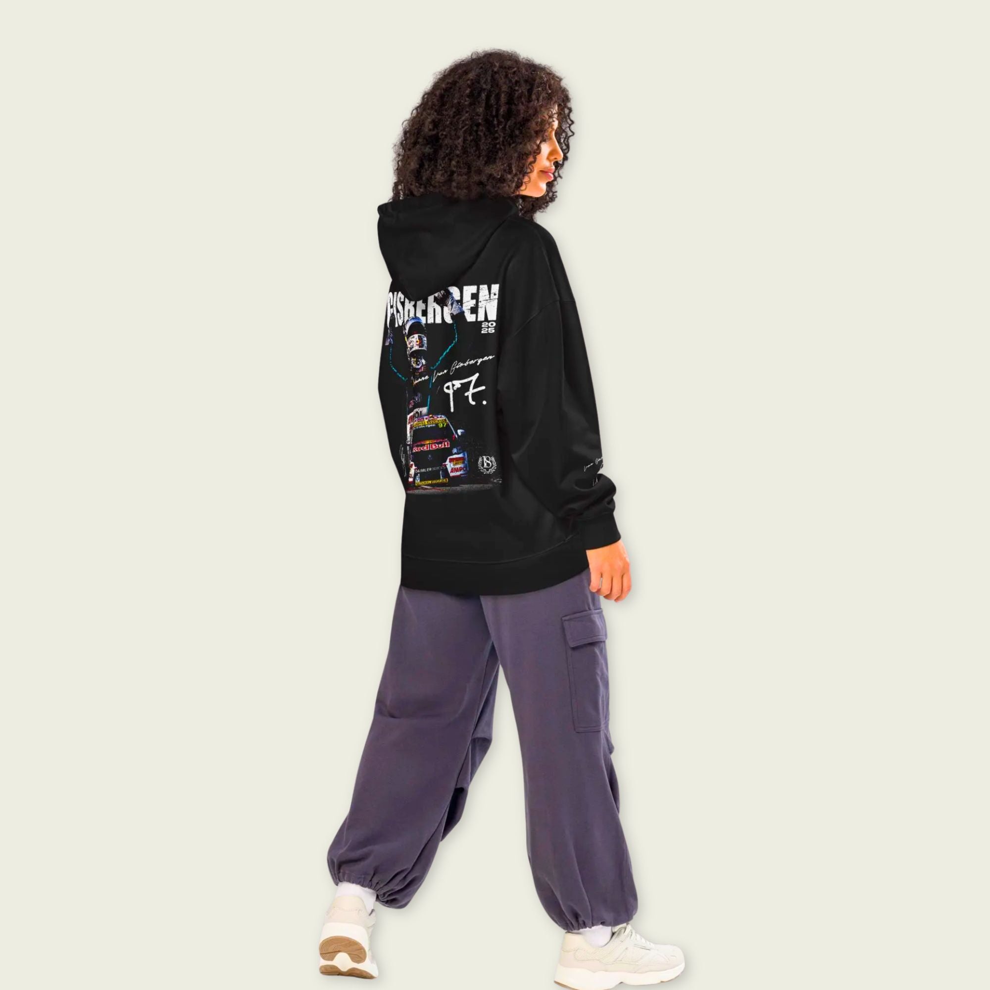 Person wearing a black hoodie with graphic designs on the back, standing against a plain background