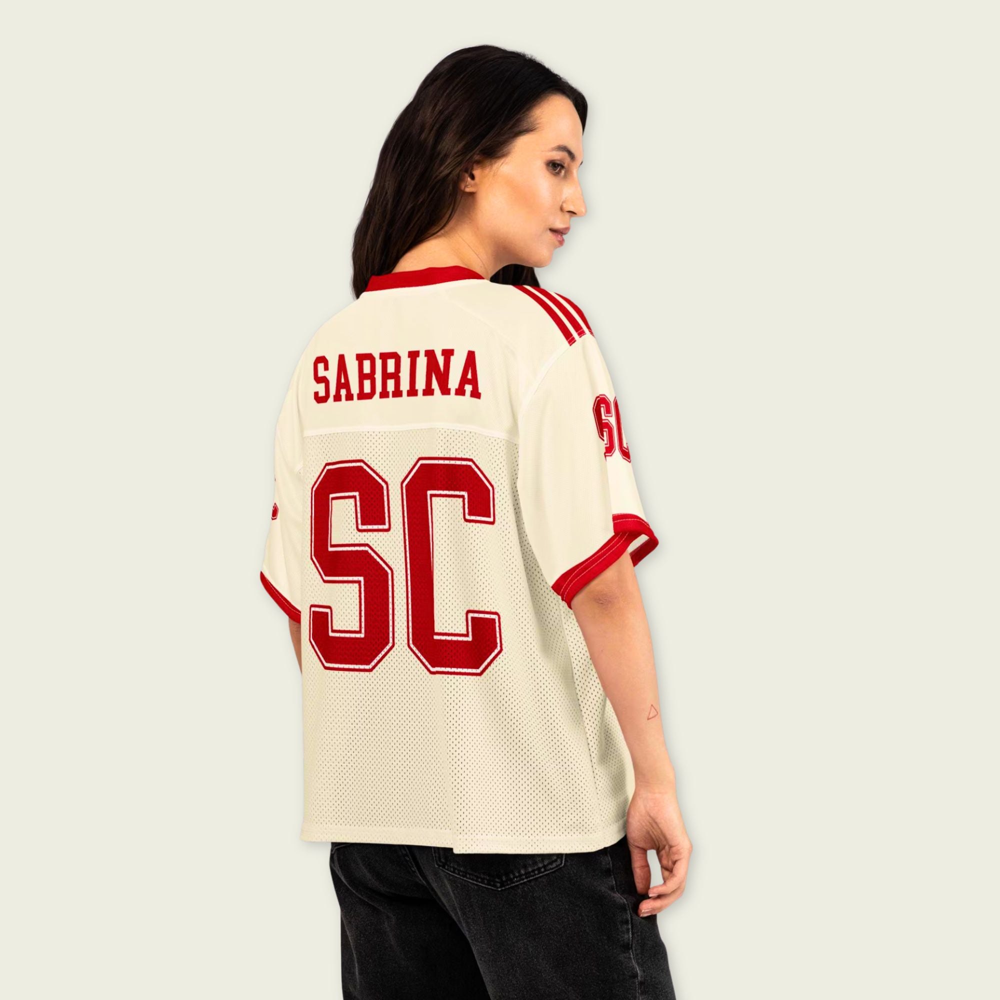 Person wearing a cream sports jersey with red lettering on a plain background