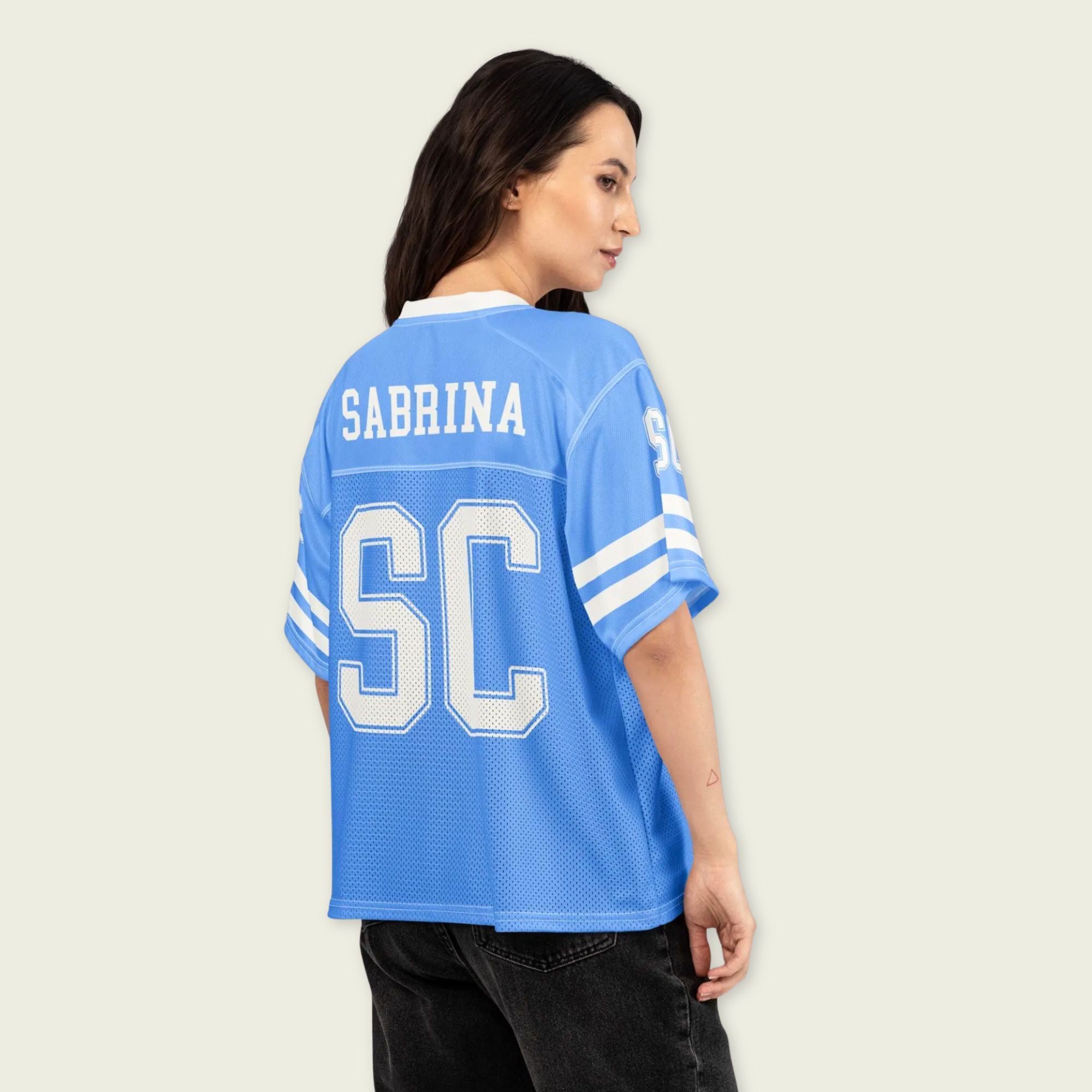 Person wearing a blue sports jersey with 'Sabrina' and 'SC' printed on it, against a plain background.