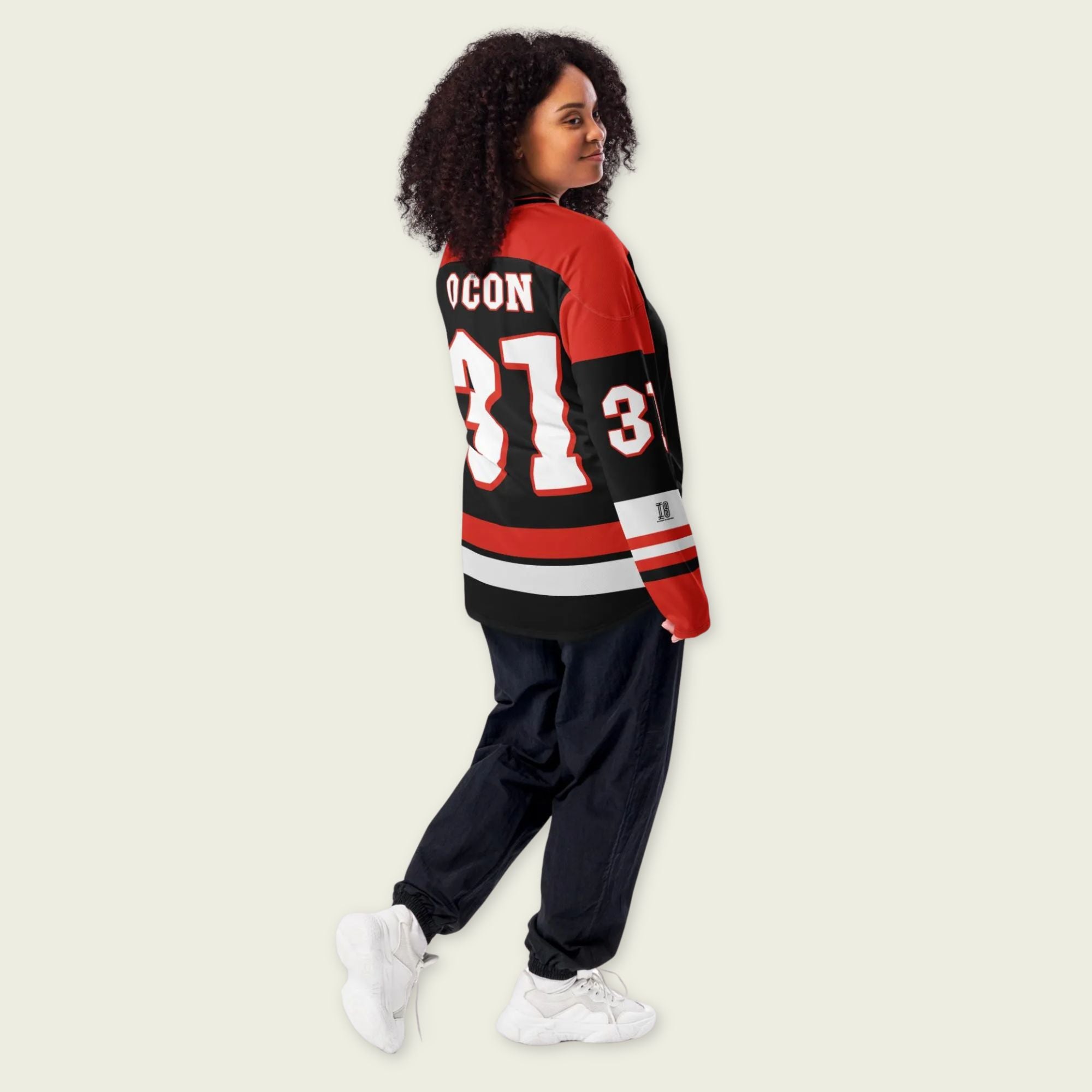 Person wearing a black and red sports jersey with the number 31 on a beige background