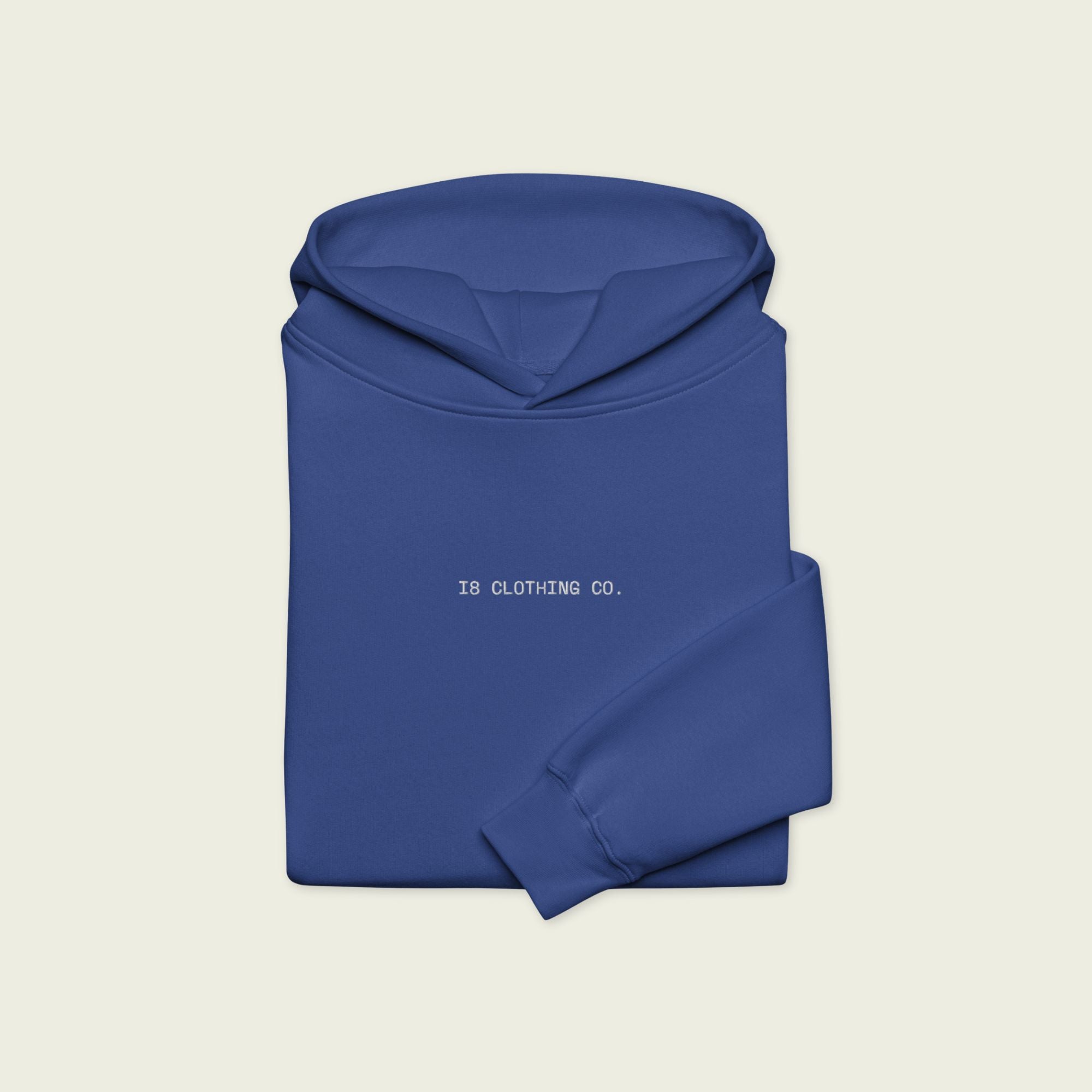 Folded blue hoodie with '18 Clothing Co.' text on a beige background