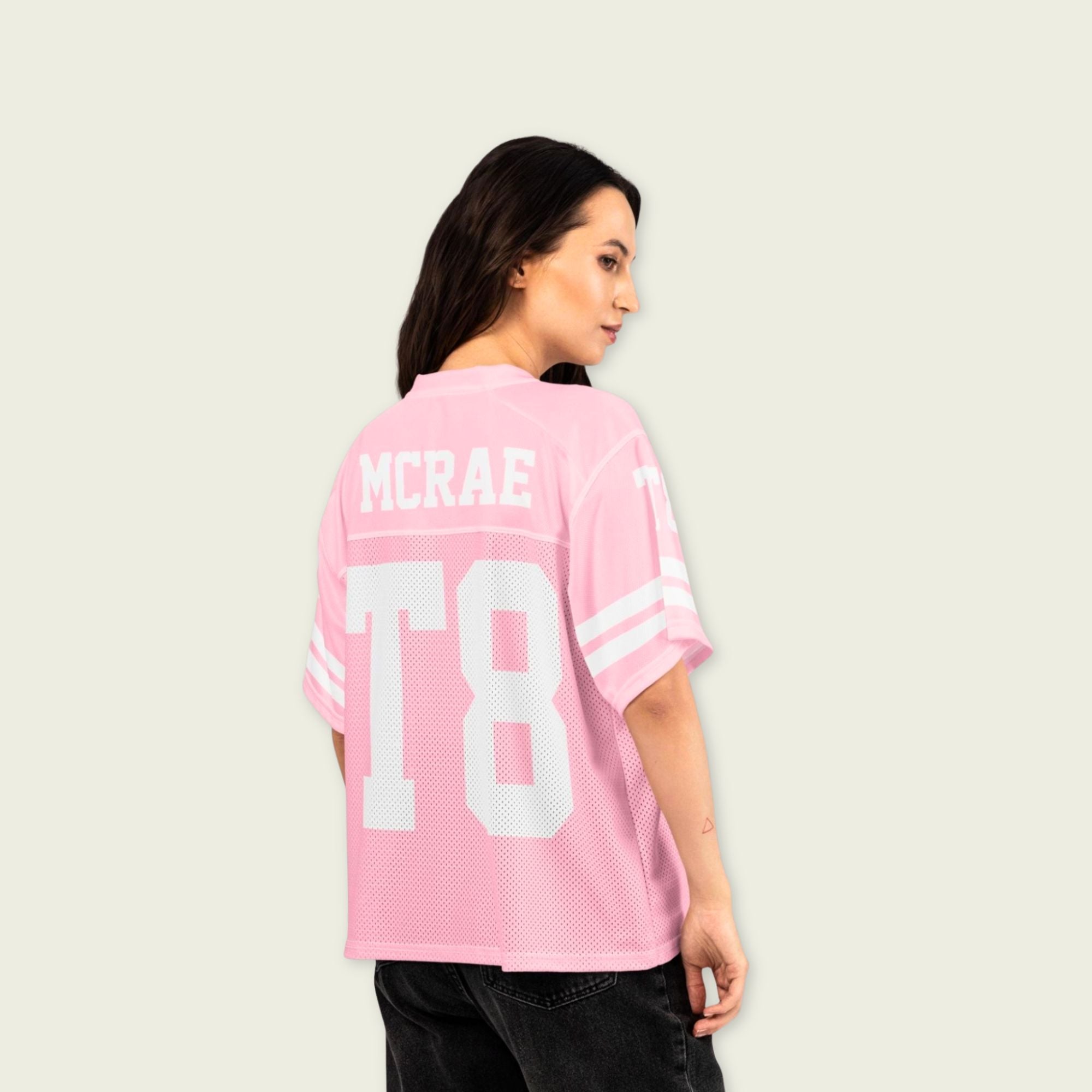 Person wearing a pink sports jersey with 'MCREA' and 'T8' printed on it against a plain background