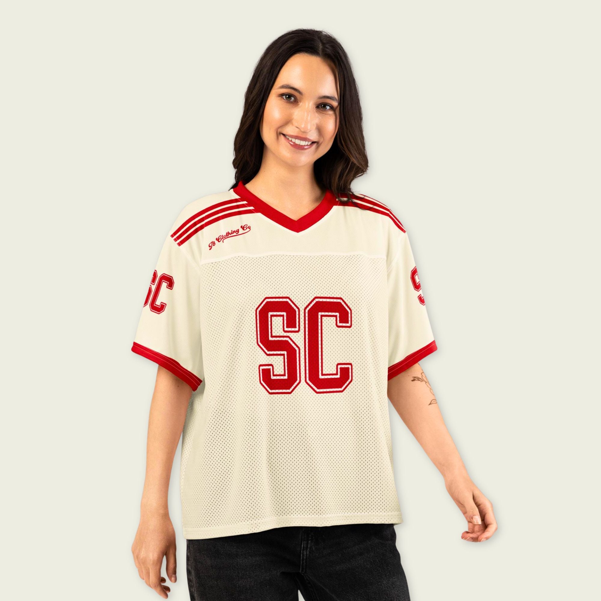 Woman wearing a cream sports jersey with red accents and 'SC' logo on a plain background