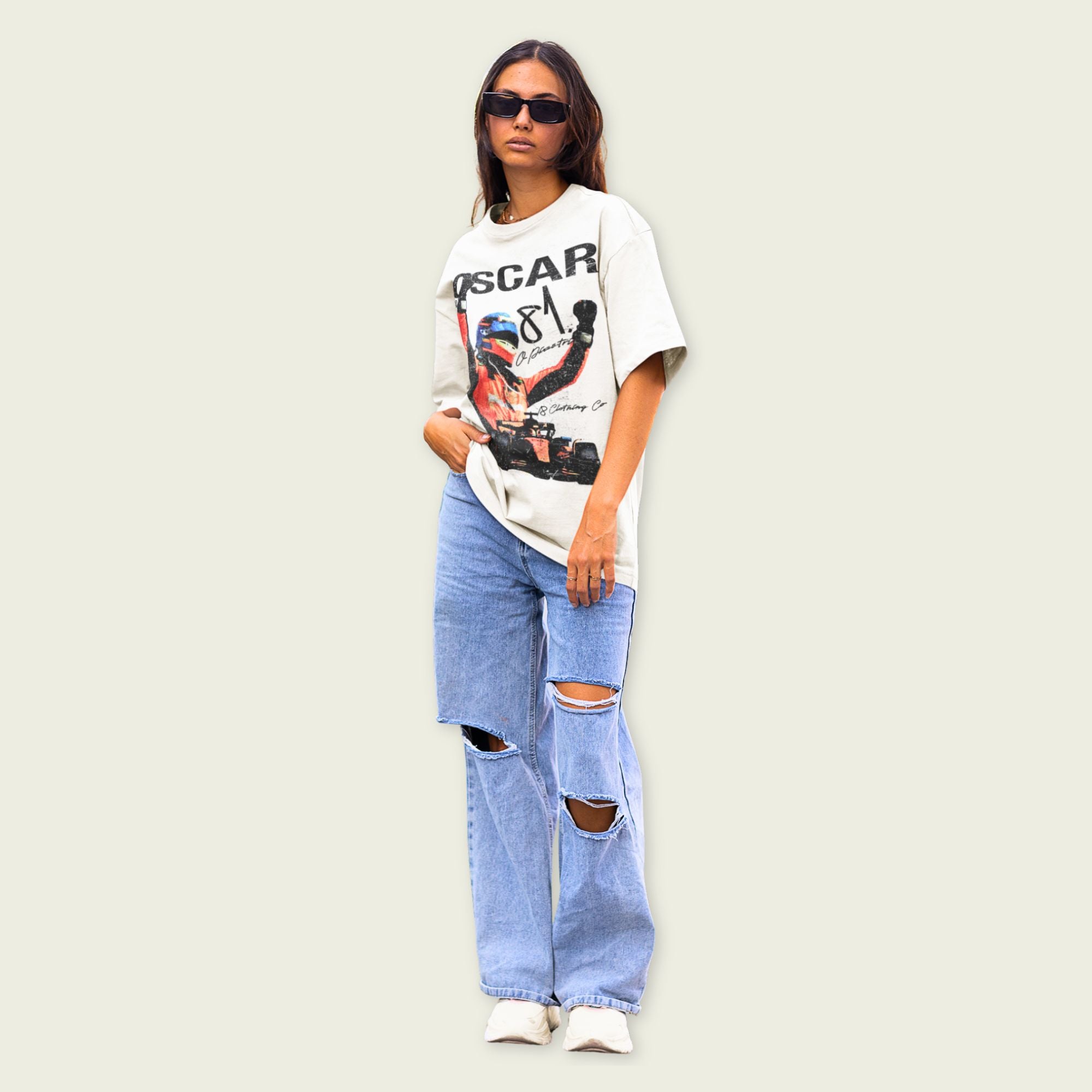 Person wearing a graphic t-shirt and ripped jeans on a plain background