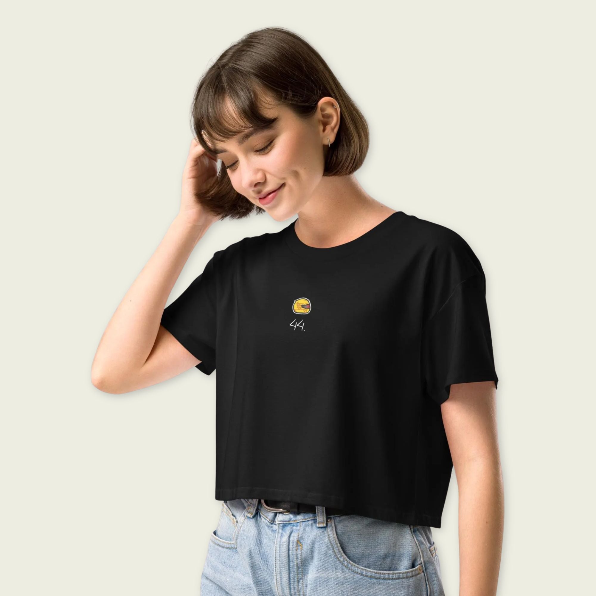 Woman wearing a black t-shirt with a small logo on a plain background