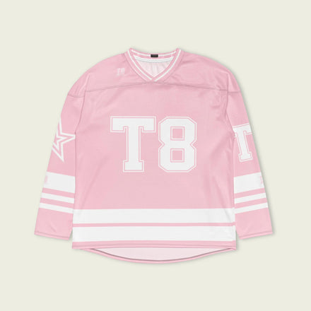 A pink and white hockey jersey with the name Mcrae in white on the front and back. Also T8 in white on the front and back.