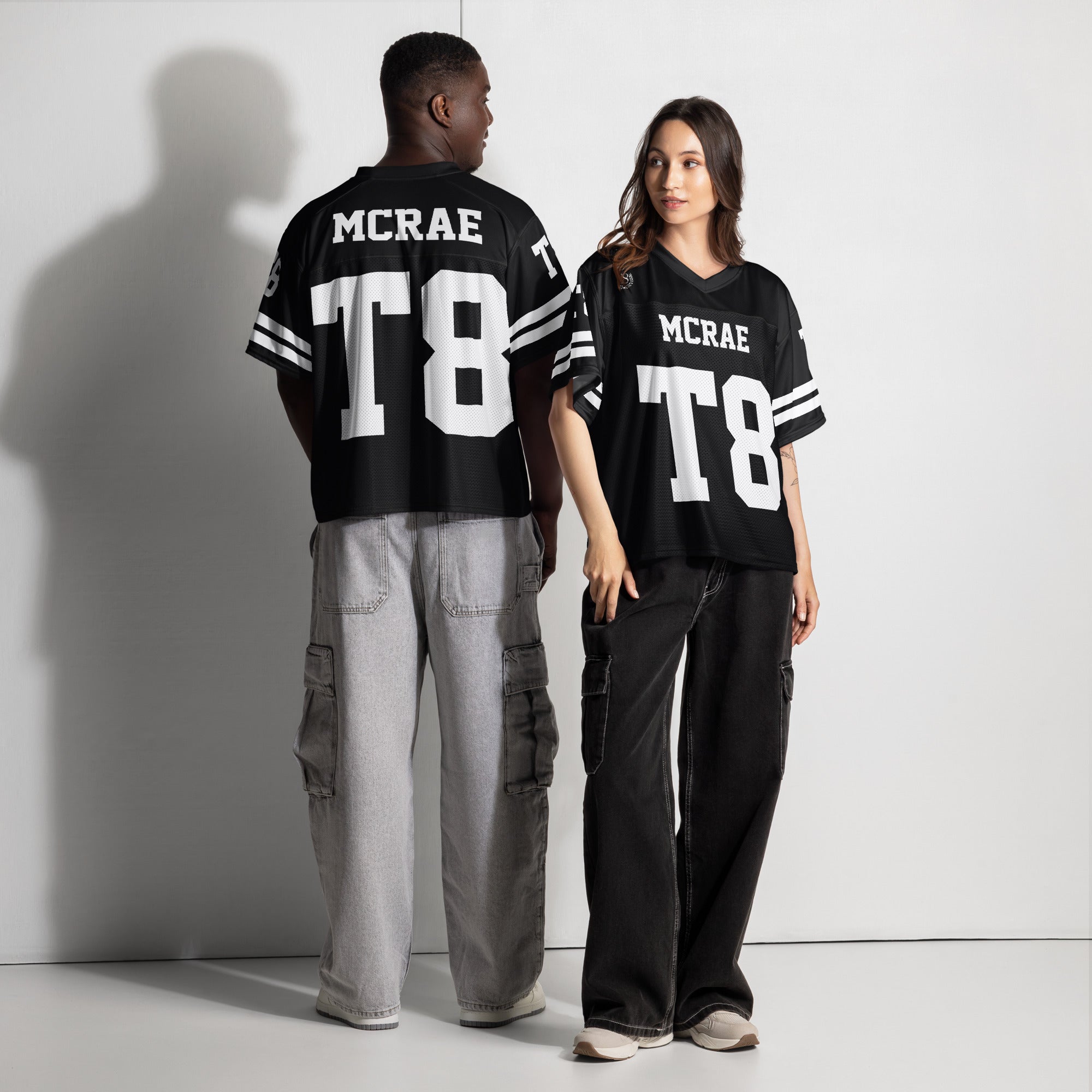 Two people wearing black jerseys with 'MCRAE' and 'T8' printed on them, standing against a white background.