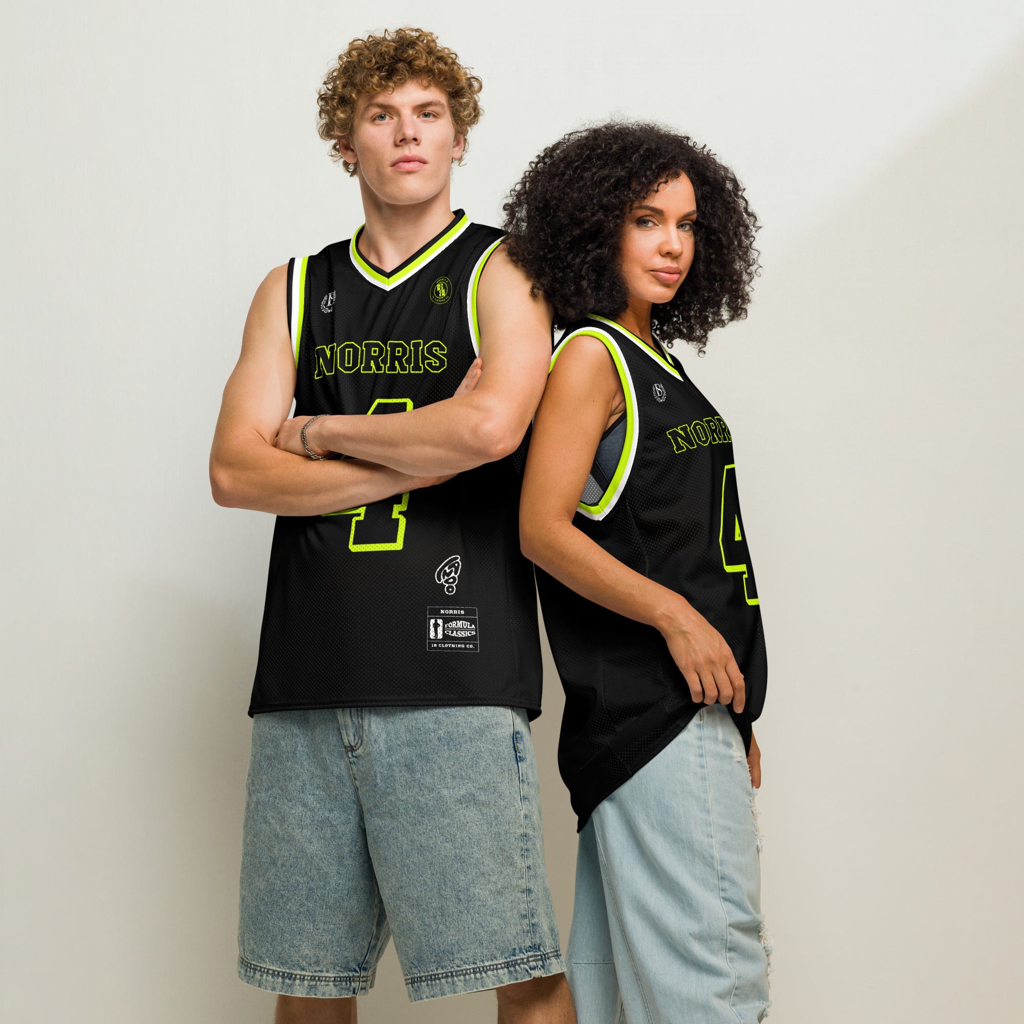 Two people wearing black basketball jerseys with yellow text against a plain background