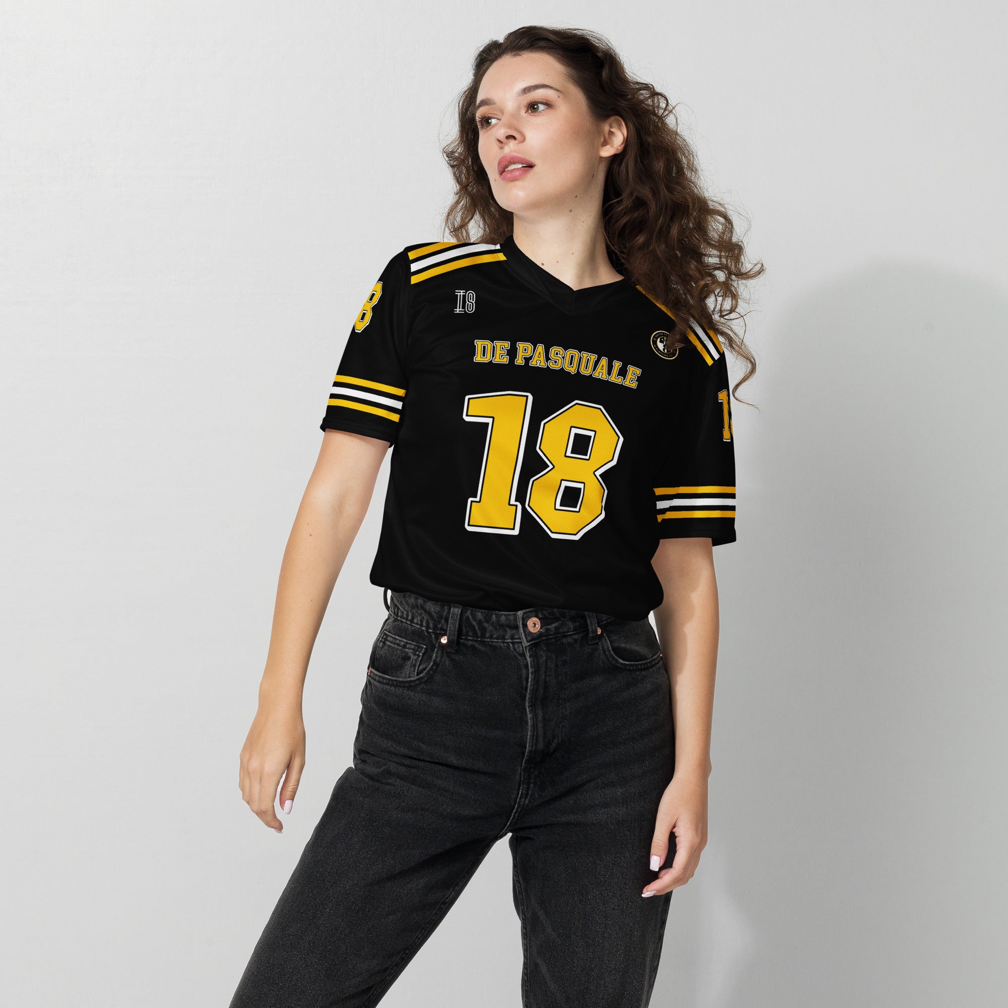 Woman wearing a black sports jersey with yellow and white details on a plain background
