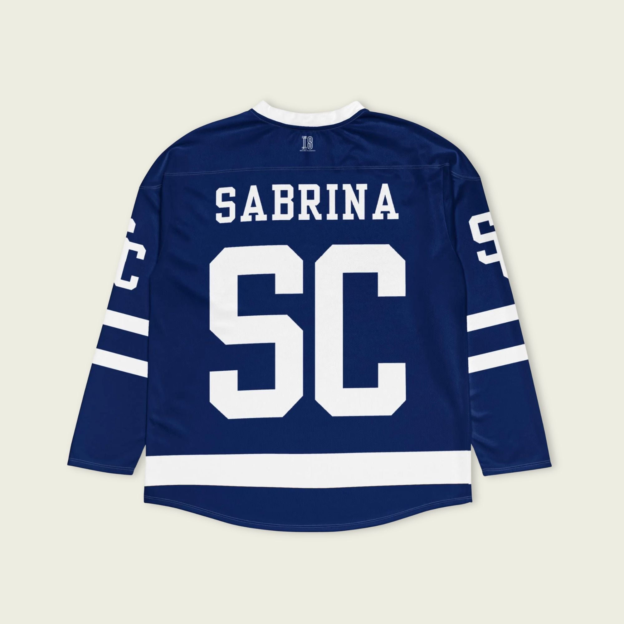 Blue hockey jersey with 'Sabrina SC' printed on the back against a beige background