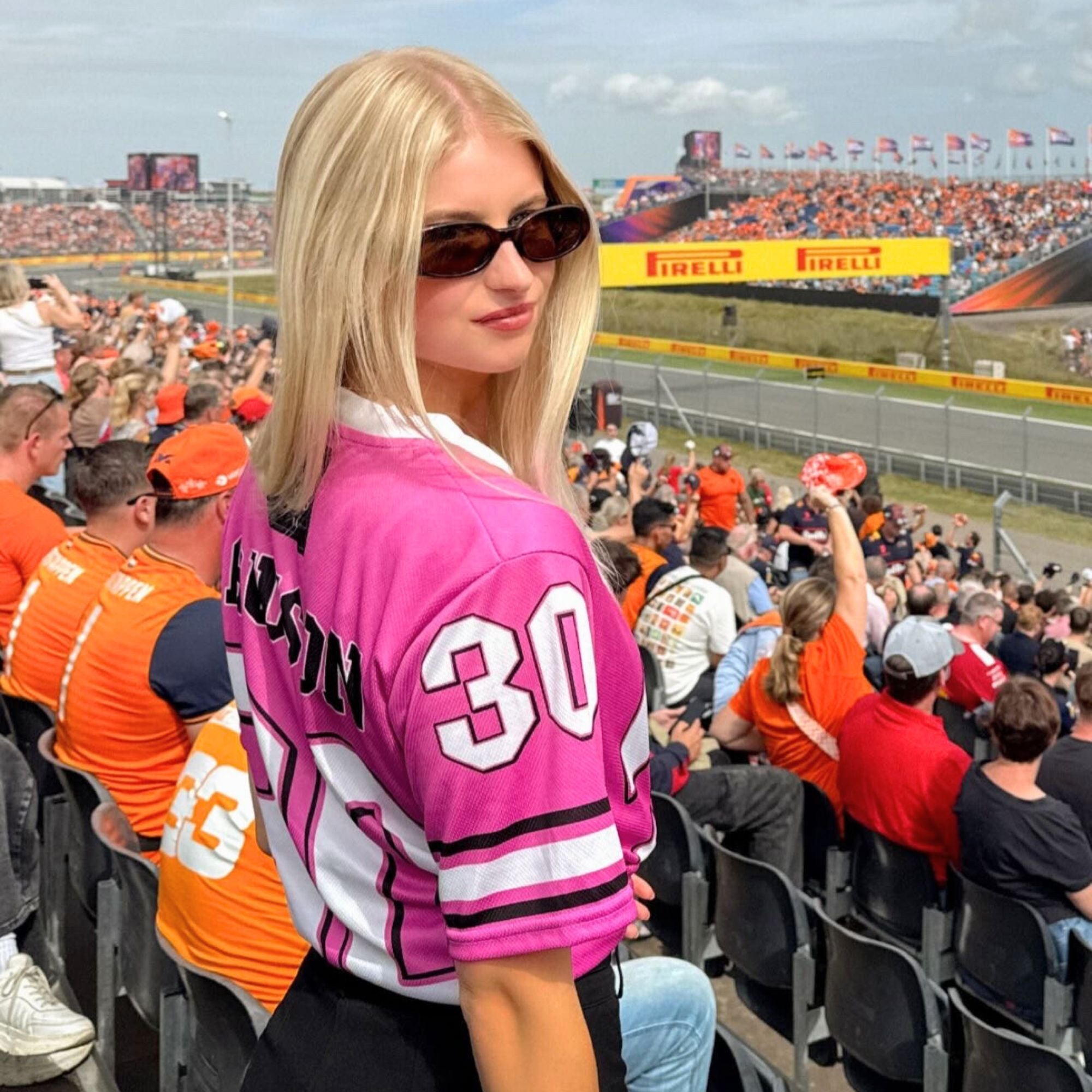 Woman in a pink sports jersey with number 30 at a race track event