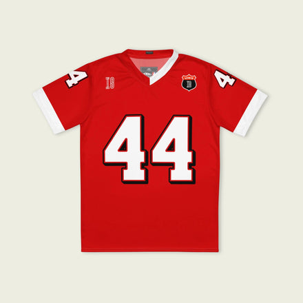 A red and white football jersey with Lewis Hamilton's Ferrari  F1 racing number 44 on the back and front in white. It has the name Hamilton in red on the front and back as well.
